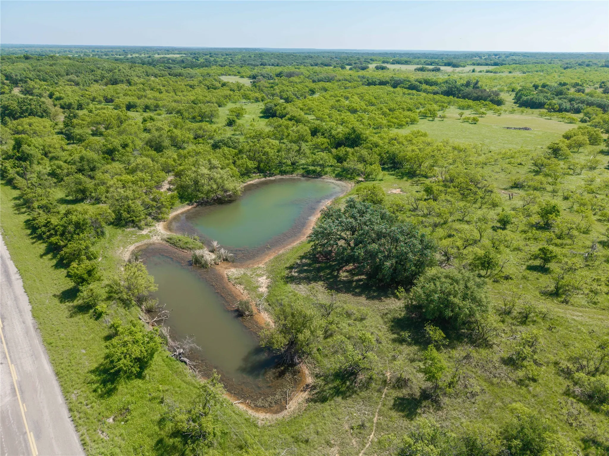 Expansive green landscape featuring two bodies of water, mature trees, and varied topography