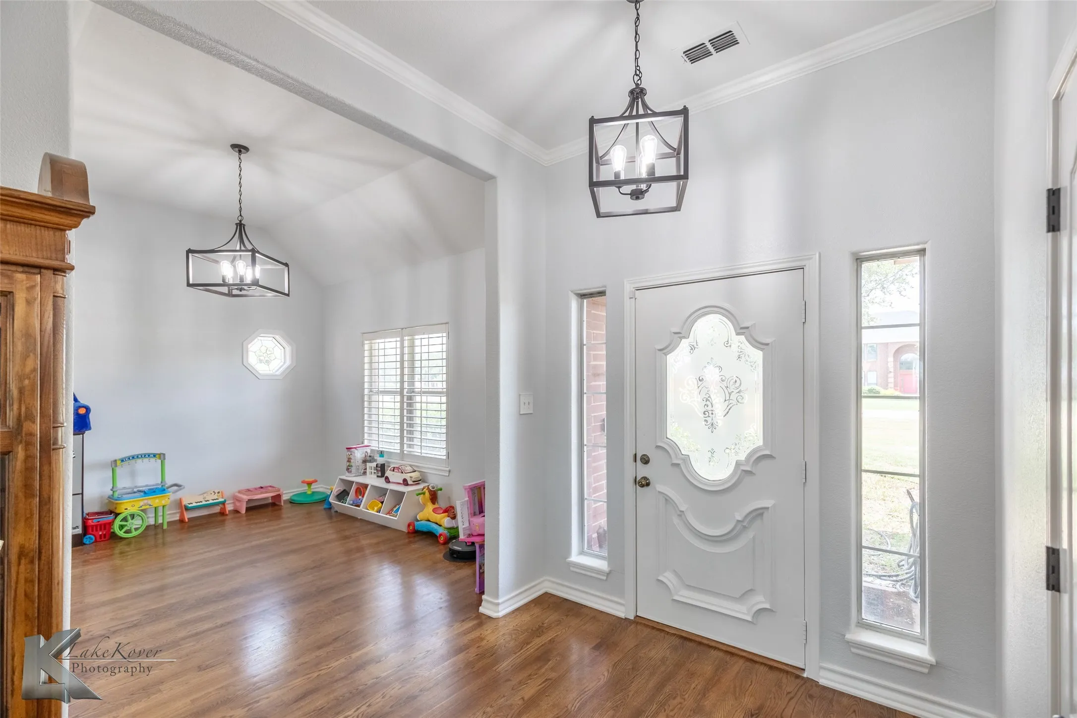 Entrance foyer featuring a chandelier, wood finished floors, ornamental molding, and vaulted ceiling