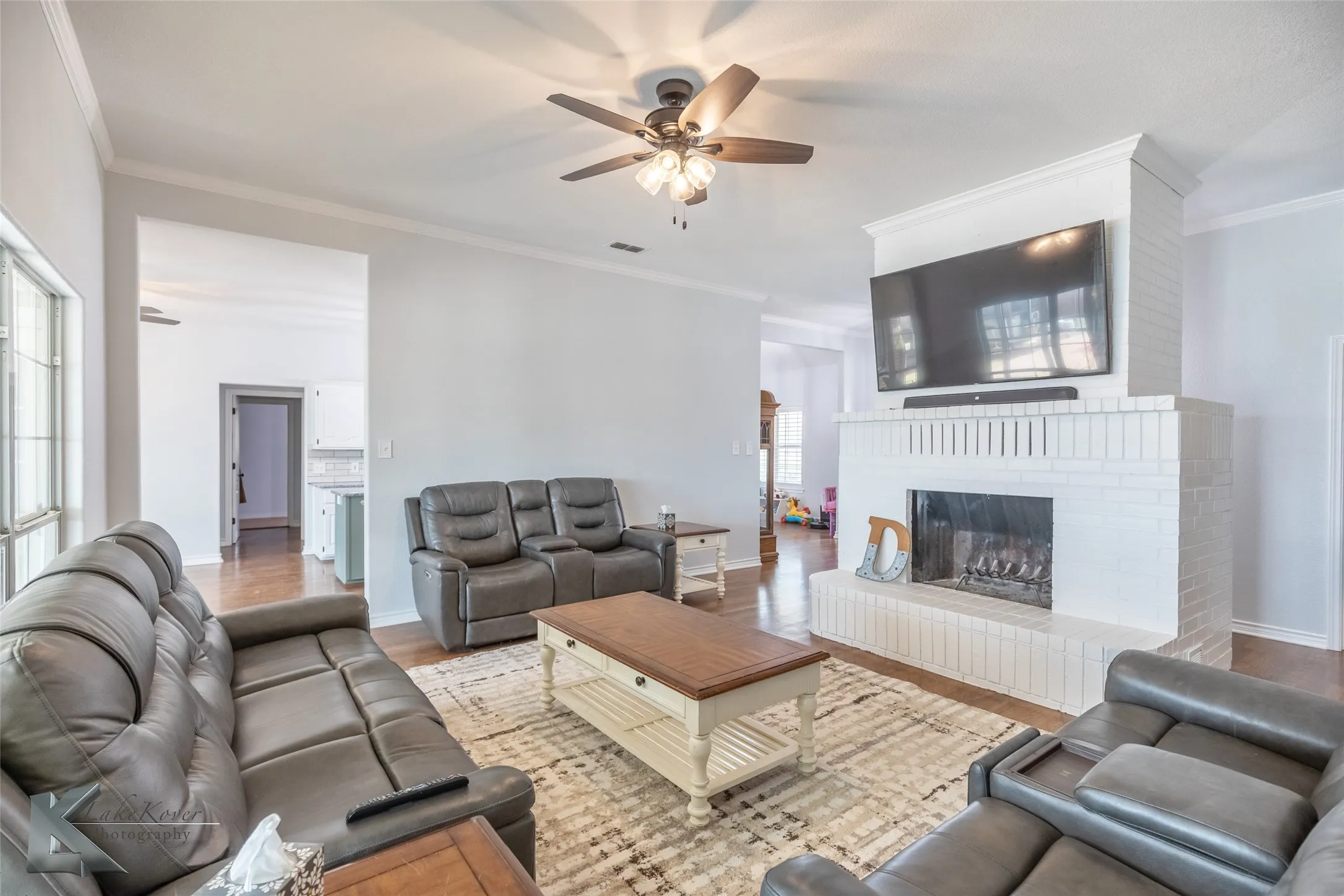 Living area featuring ceiling fan, crown molding, wood finished floors, and a fireplace