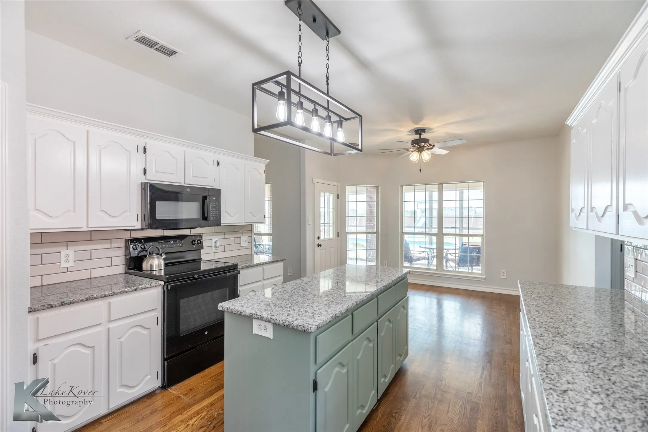 Kitchen featuring black appliances, a center island, ceiling fan, white cabinets, and tasteful backsplash