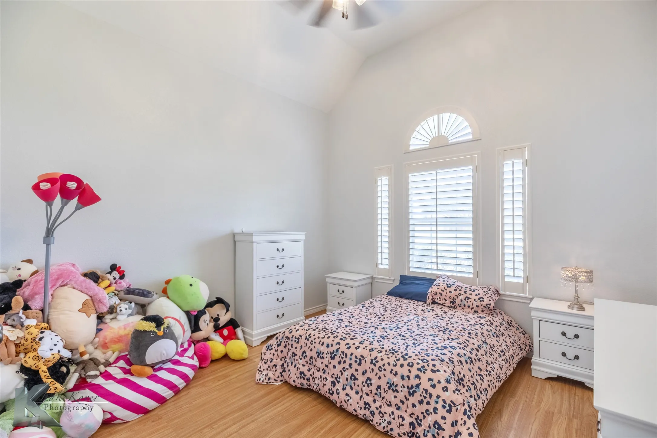 Bedroom featuring multiple windows, wood finished floors, vaulted ceiling, and ceiling fan