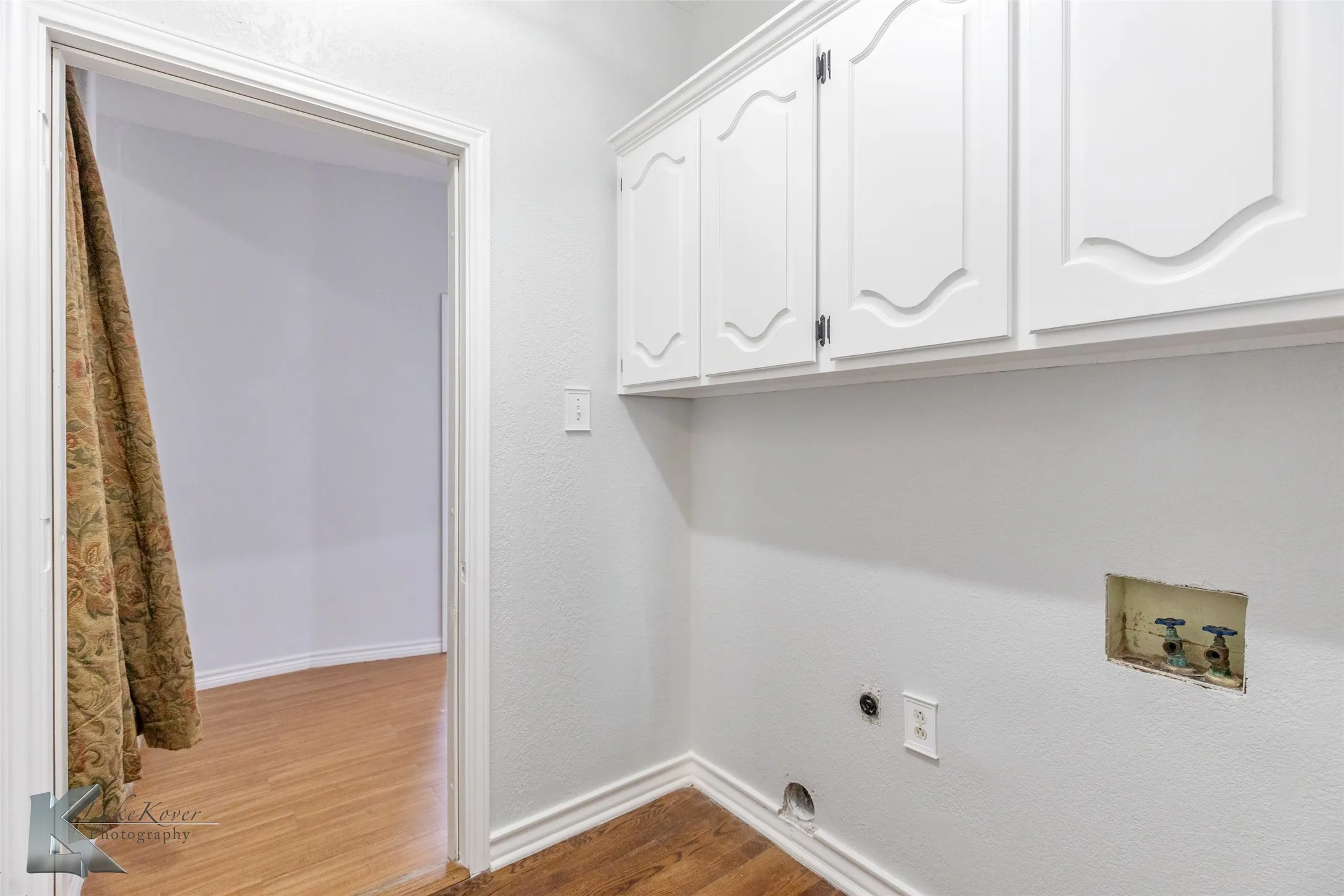 Washroom with washer hookup, cabinet space, wood finished floors, and electric dryer hookup