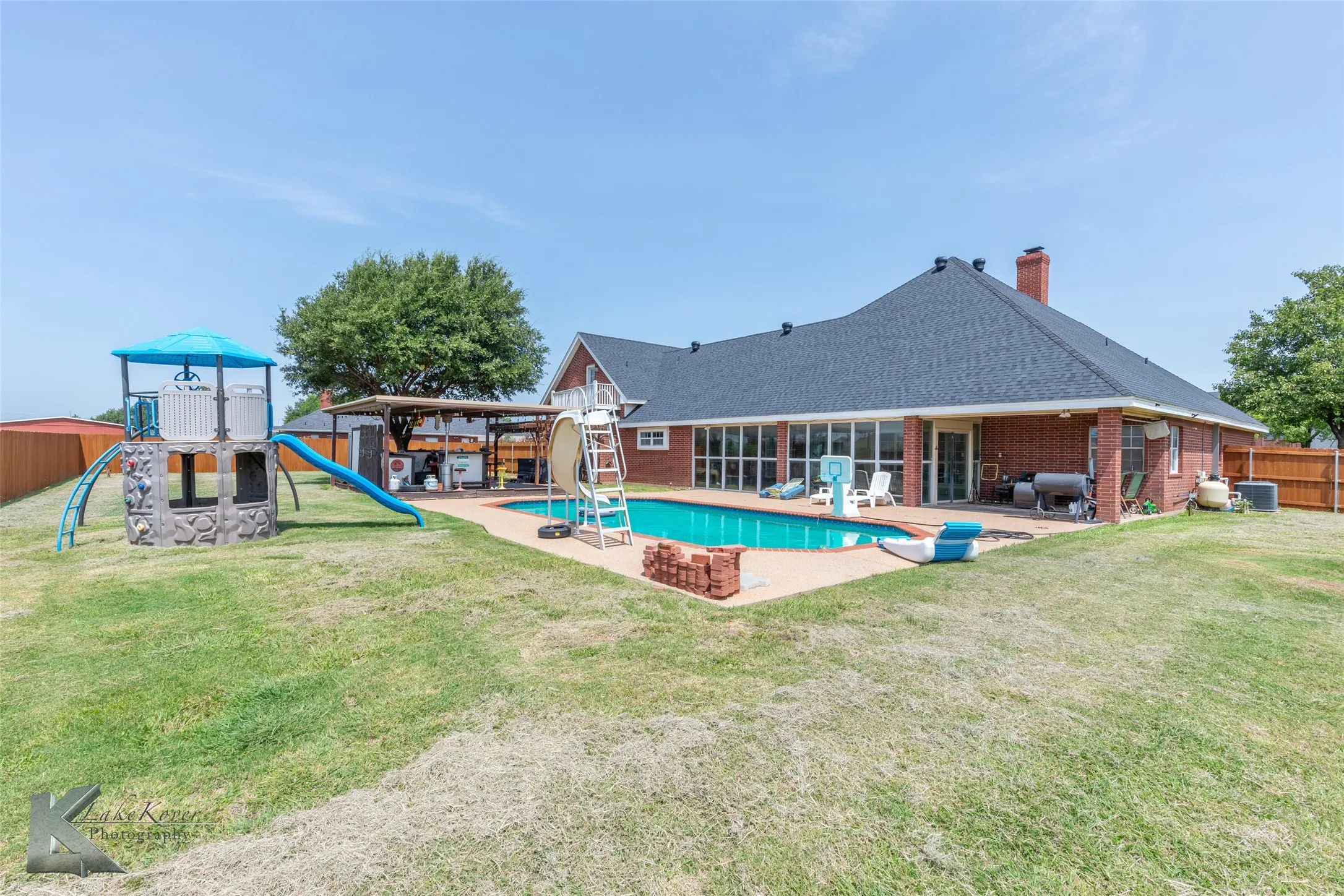 View of swimming pool featuring a playground, a fenced backyard, and a patio area