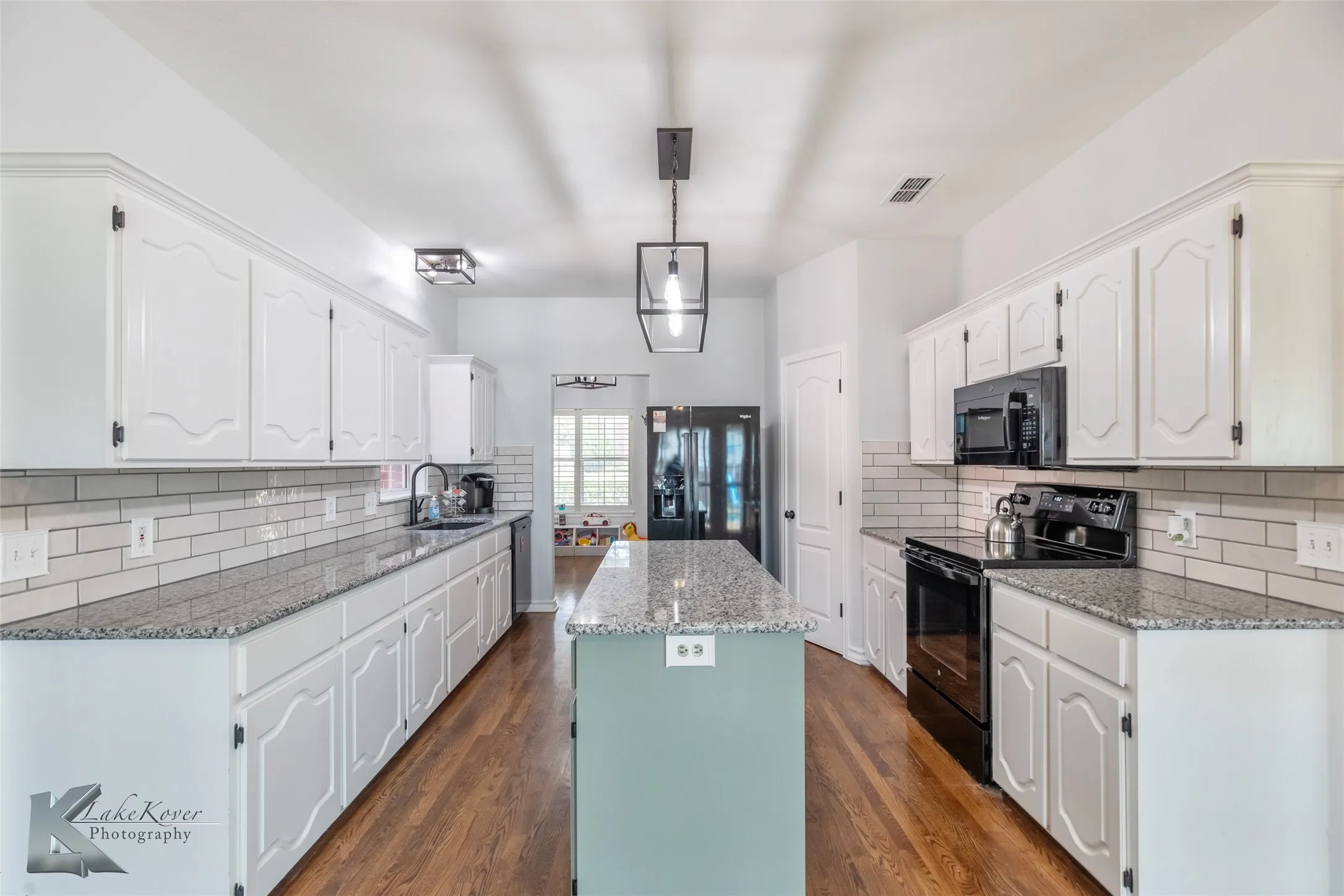 Kitchen with black appliances, a center island, white cabinetry, and backsplash
