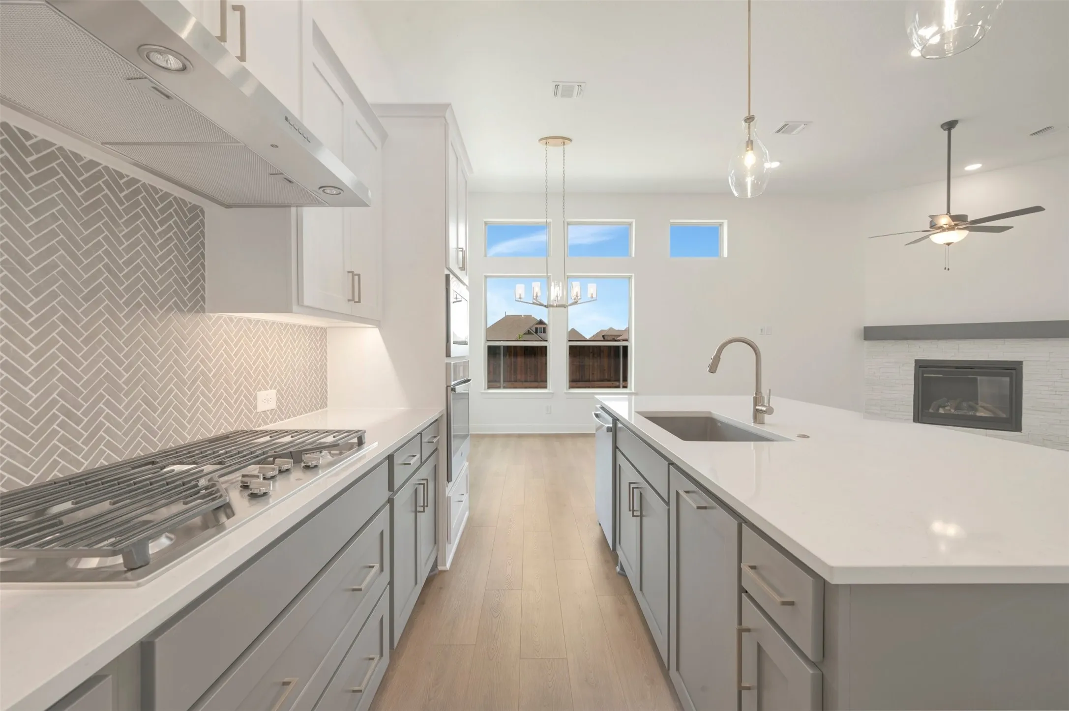 Kitchen featuring an expansive island with an undermount sink and a gas cooktop with a herringbone tile backsplash