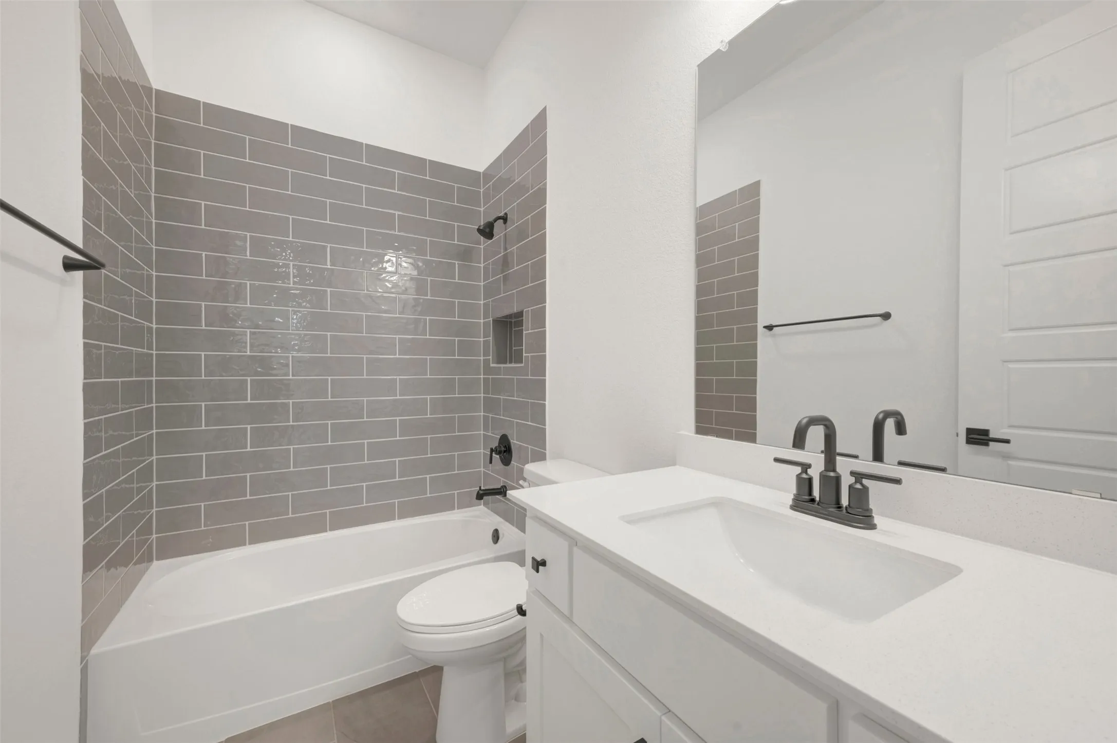 Bathroom featuring a tub/shower combination with grey subway tile surround, integrated shower niche, and matte black fixtures