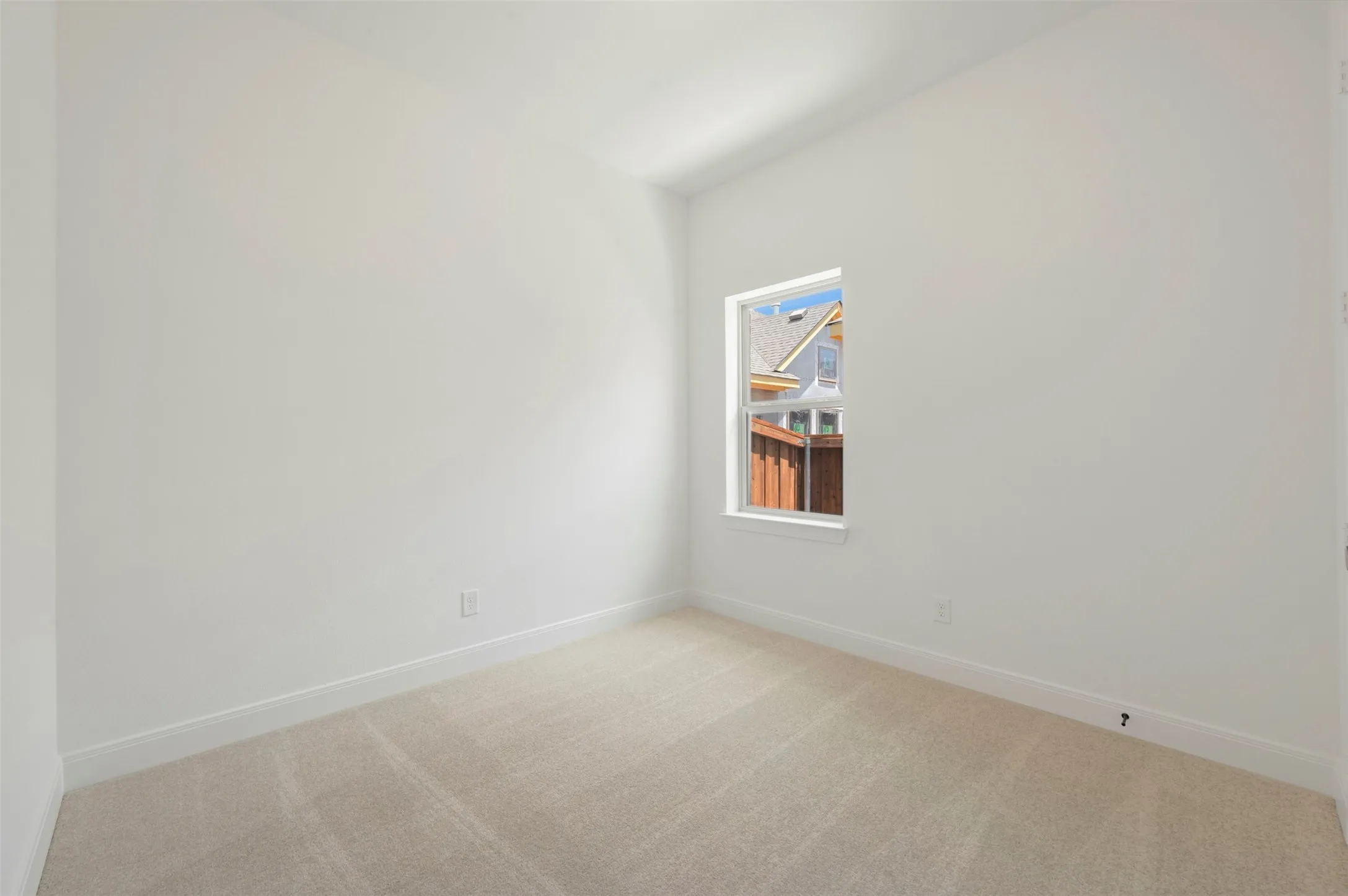 Room featuring neutral carpet flooring, white painted walls, and a single window with white trim