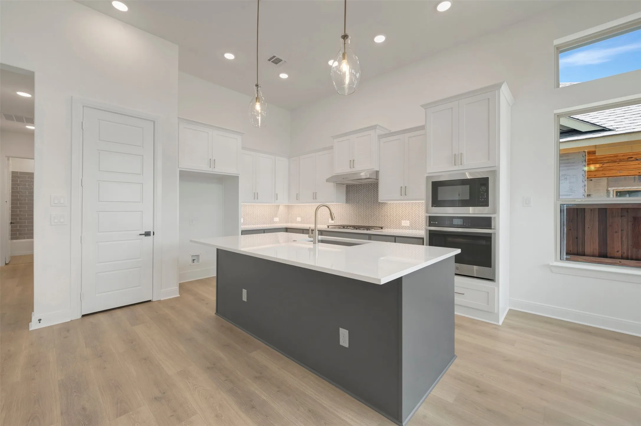 Contemporary kitchen featuring a large central island with a solid surface countertop