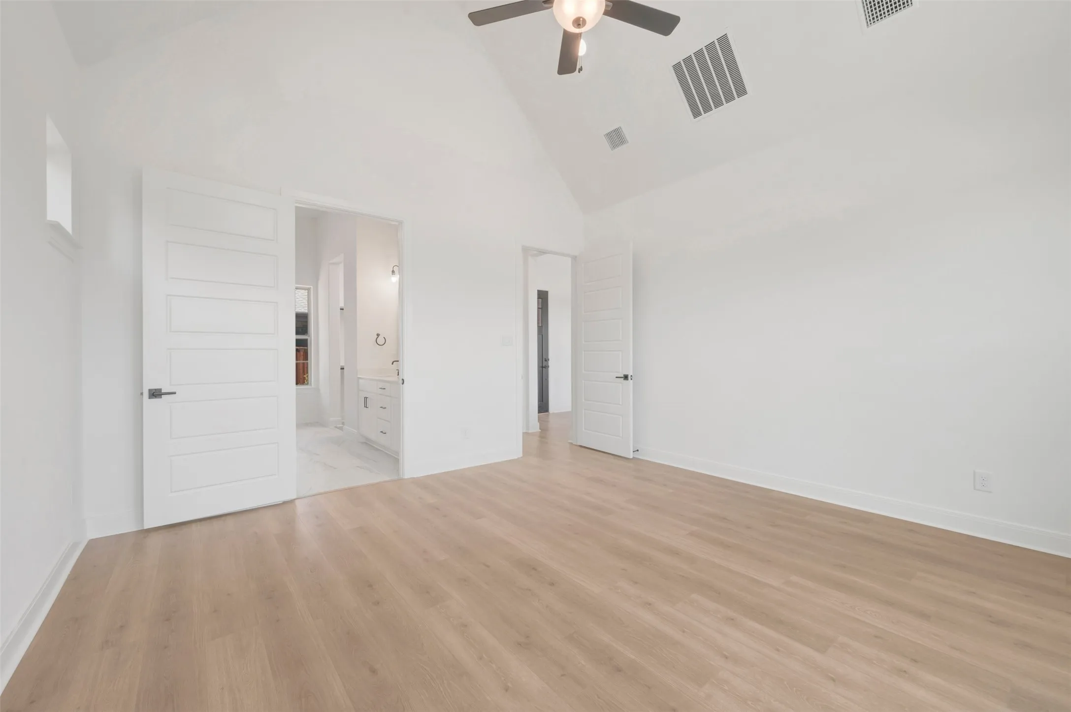 Spacious room featuring vaulted ceilings, wood-finish flooring, and white paneled doors