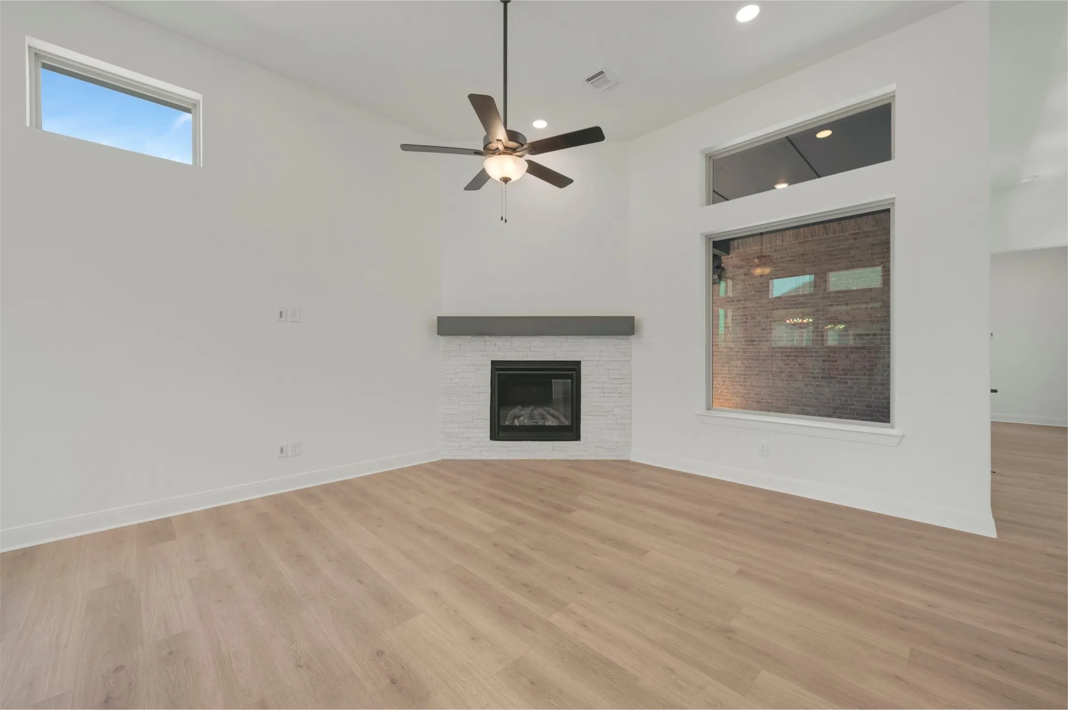 Spacious room featuring a corner fireplace with white tile surround and a wood mantel