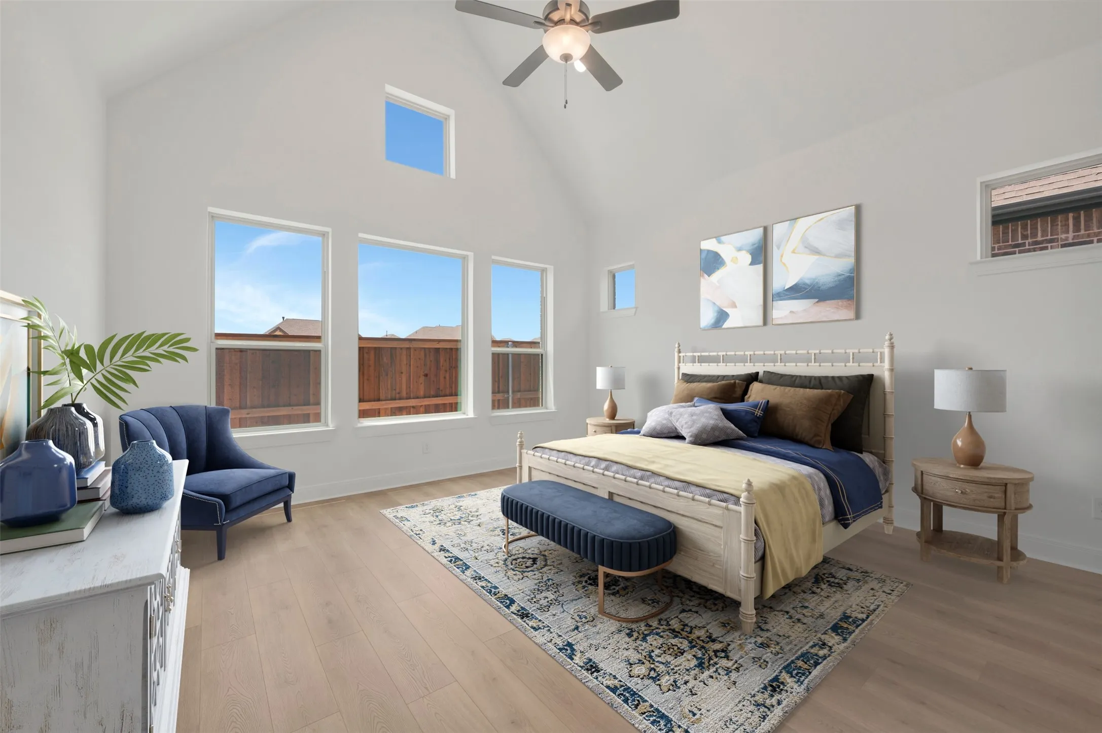 Vaulted ceiling with a ceiling fan, light wood-finish flooring, and multiple windows, including a high transom window