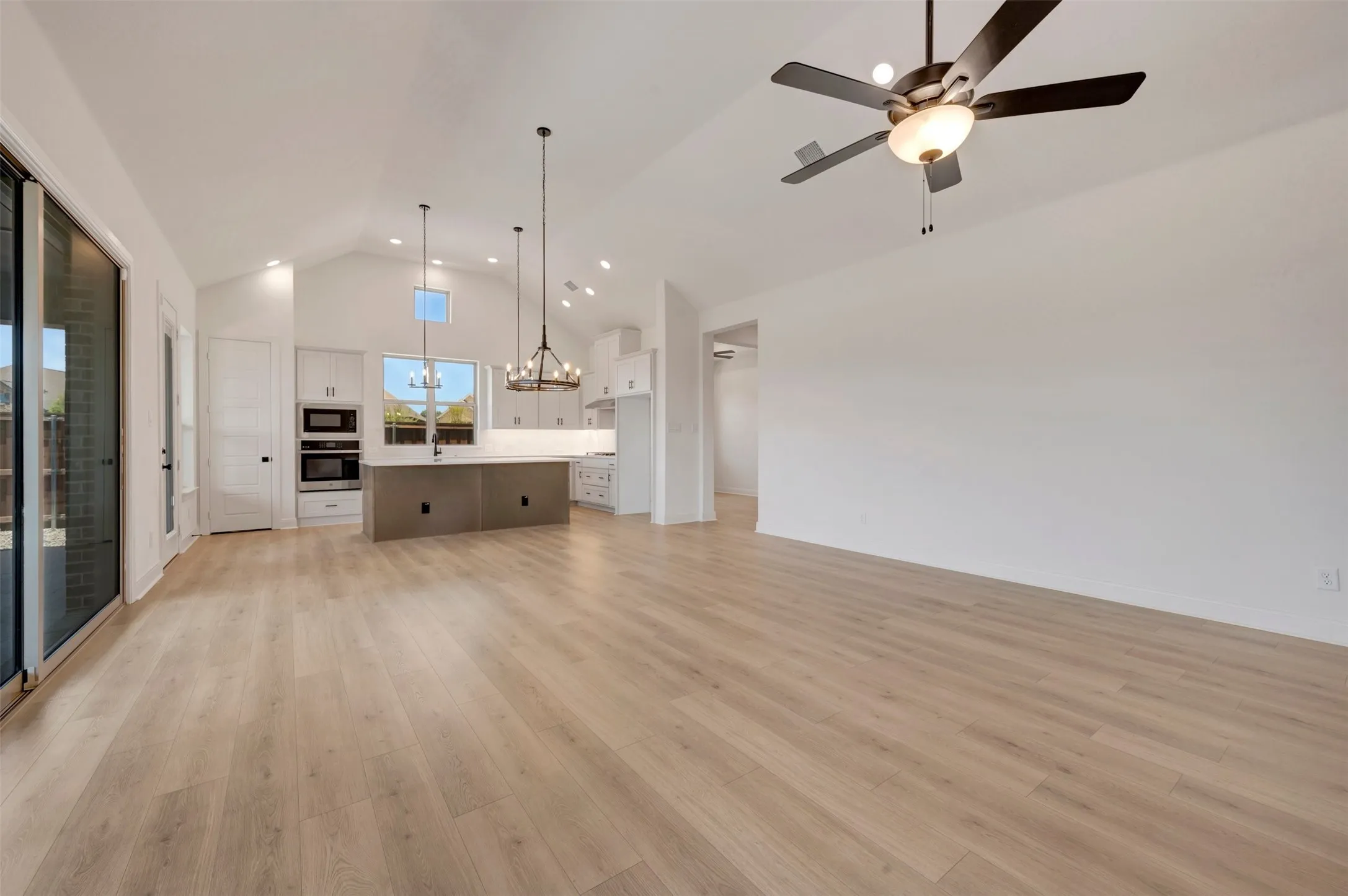 Spacious open-concept living area featuring a vaulted ceiling and light wood-finish flooring