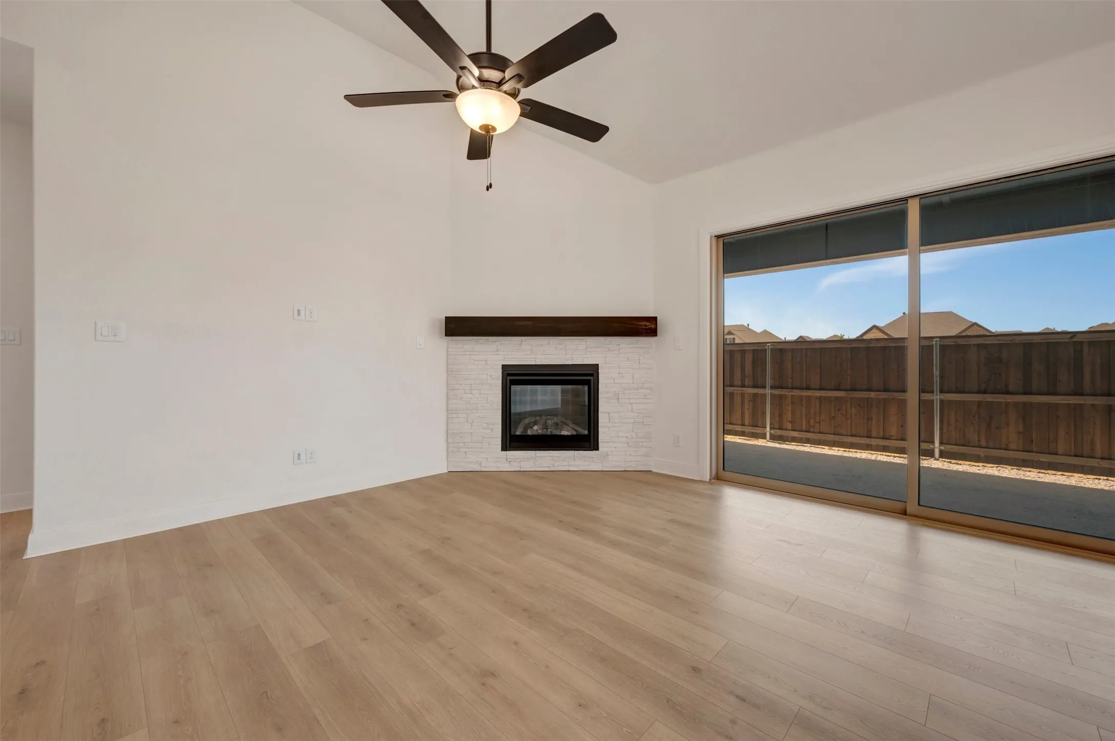 Spacious interior featuring wood-finish flooring, a vaulted ceiling, and a ceiling fan with integrated lighting