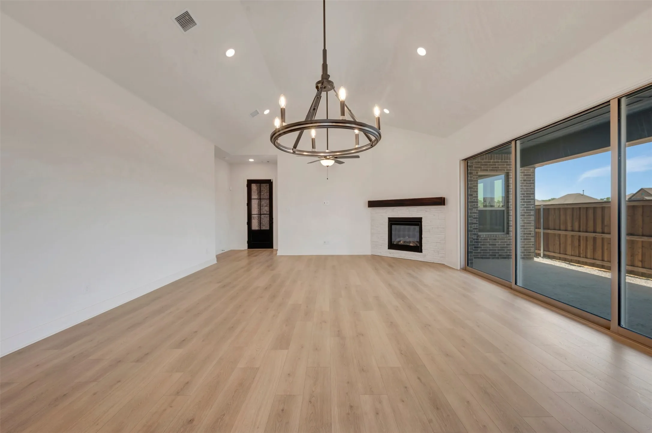 Spacious living area featuring light wood-finish flooring, vaulted ceilings, and recessed lighting