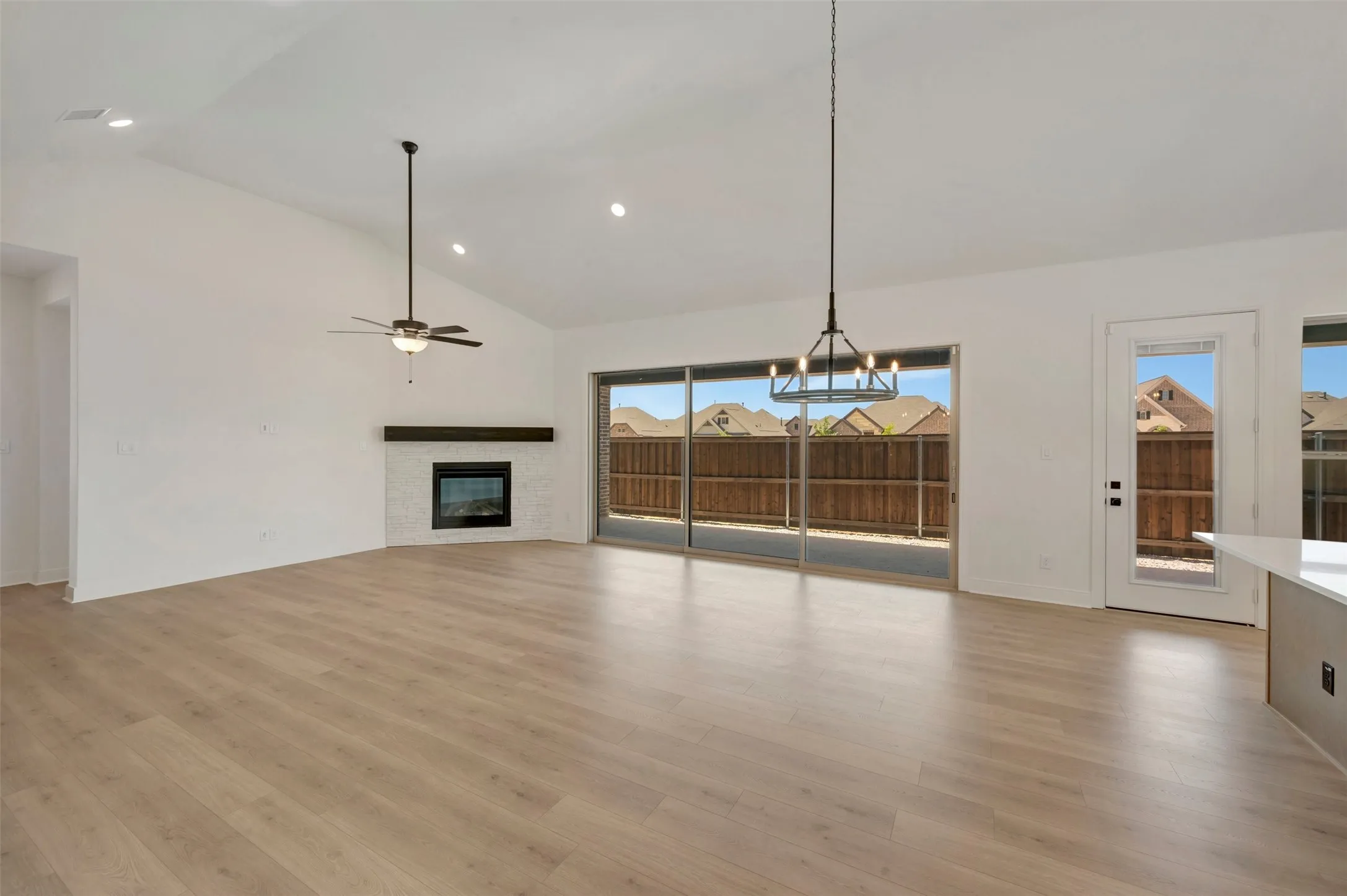 Spacious room with a vaulted ceiling, recessed lighting, and wood-finish flooring