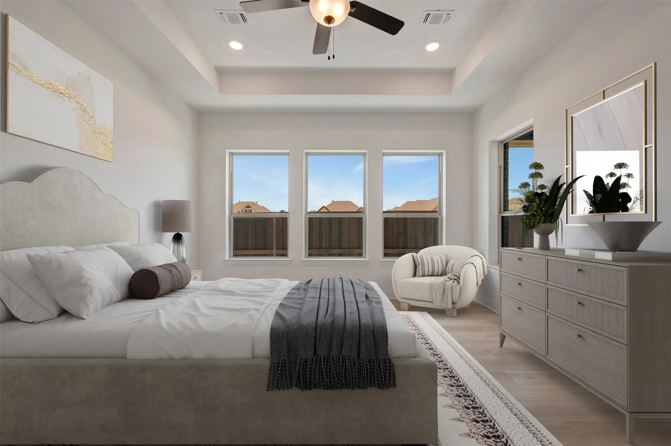 Spacious room featuring tray ceiling, recessed lighting, ceiling fan, three large windows, and wood-finish flooring