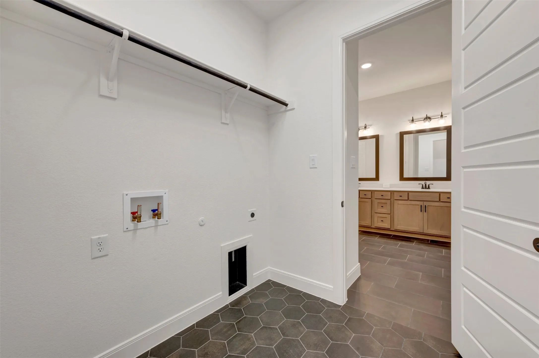 Laundry area with hexagonal floor tiles and an overhead clothing rod