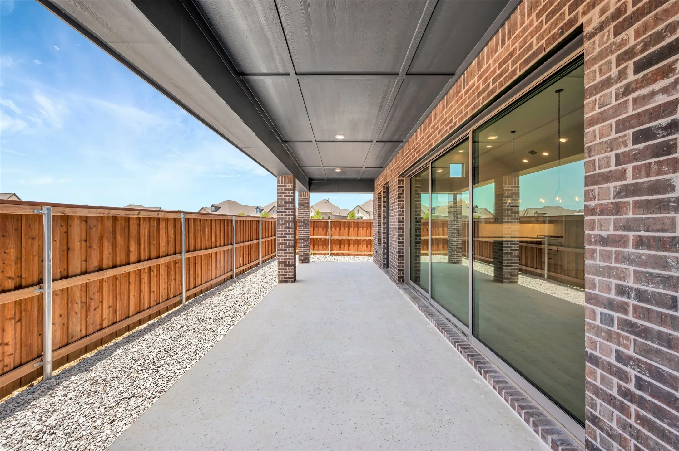 Covered patio featuring a concrete slab and exposed brick facade
