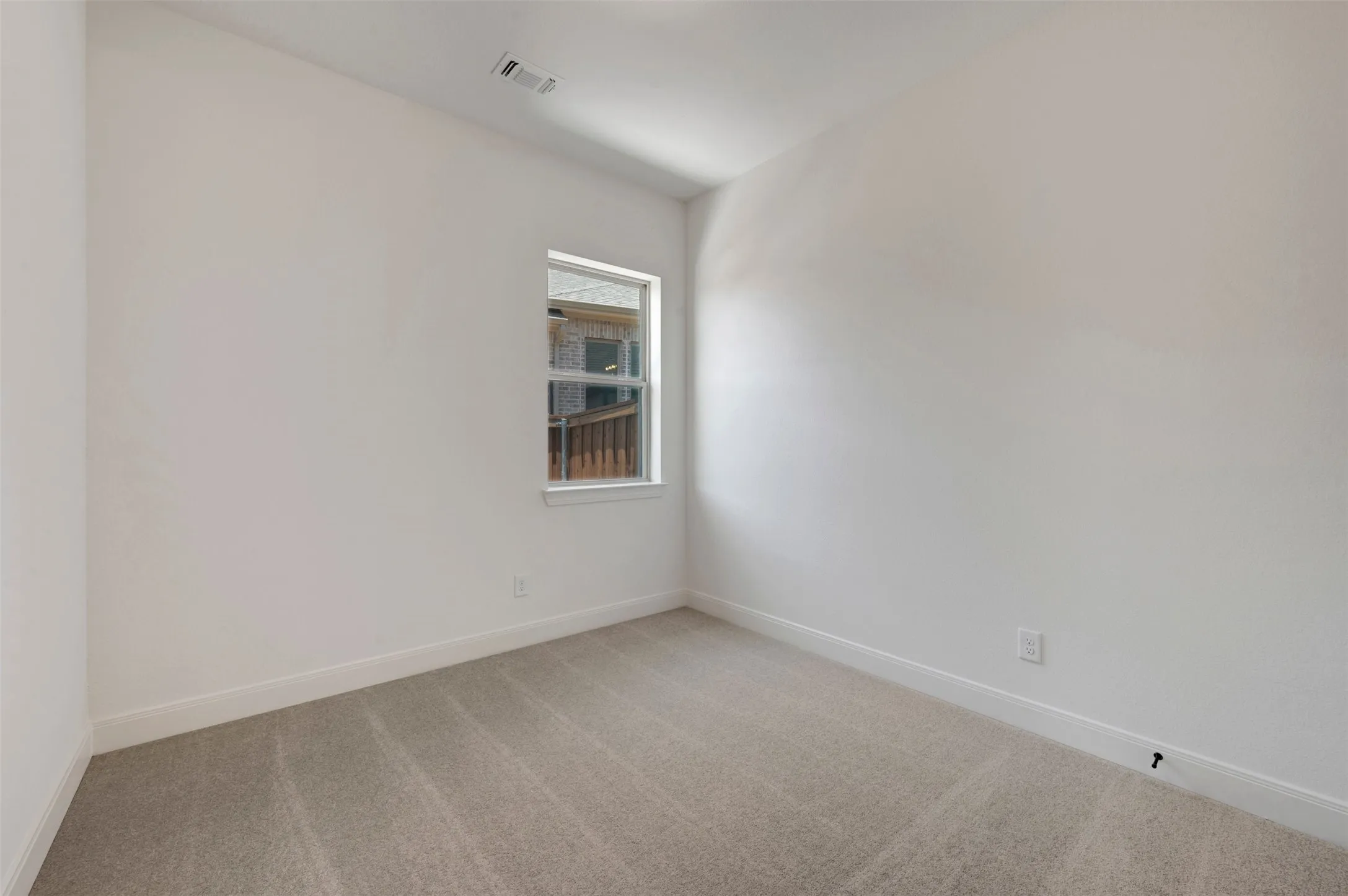 Neutral-toned room with white walls, light gray carpeting, and a single window