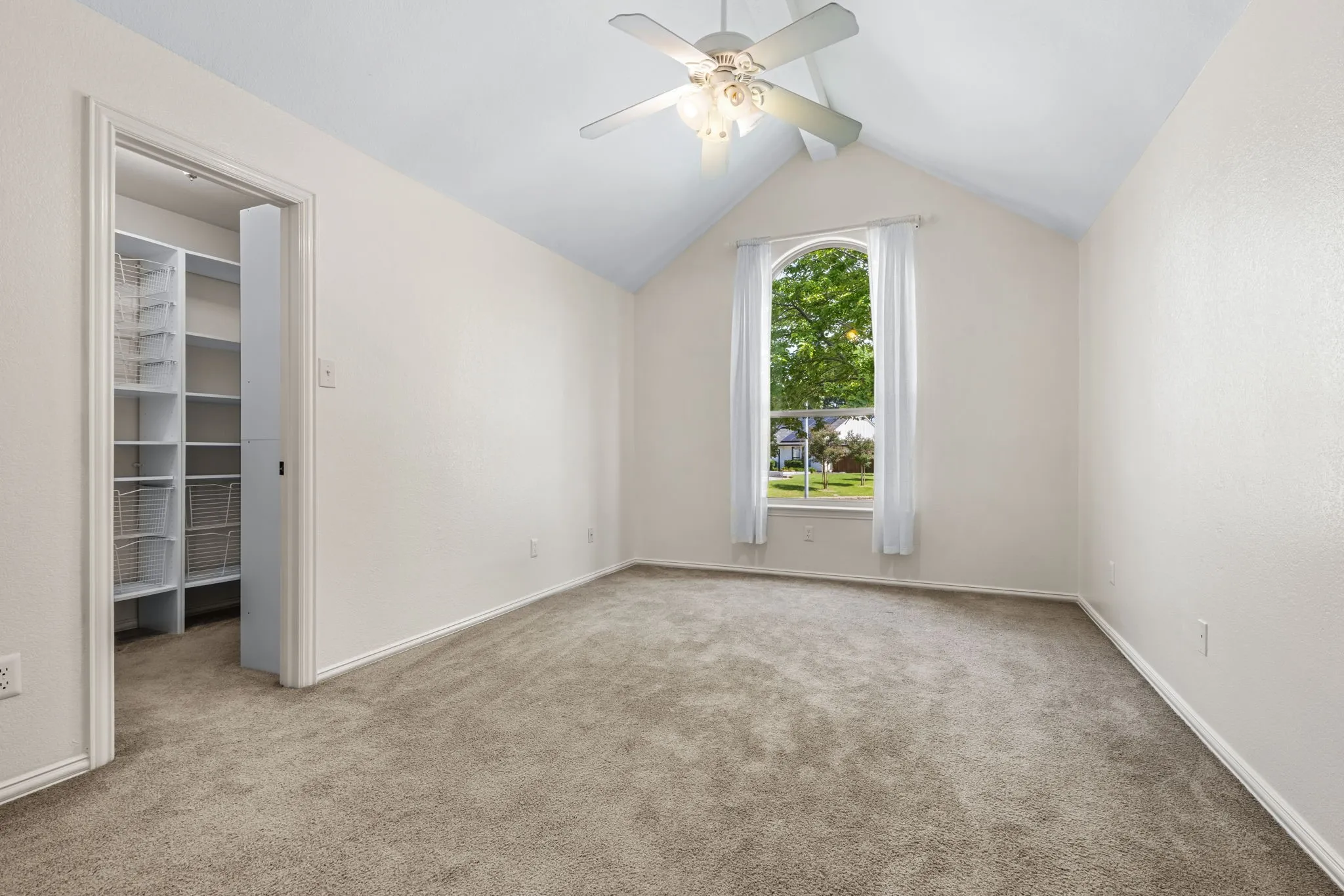 Vaulted ceiling 3rd bedroom upstairs  featuring an arched window and walk in closet