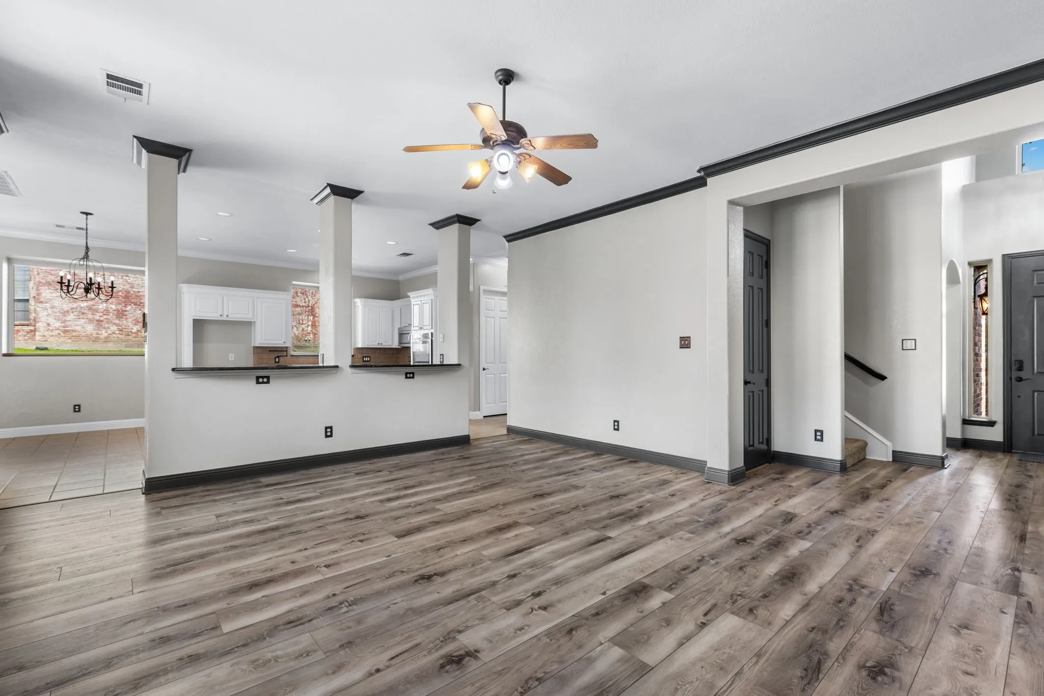 Kitchen featuring a navy blue island with a dark countertop, white perimeter cabinetry, stainless steel dishwasher, and a tile backsplash