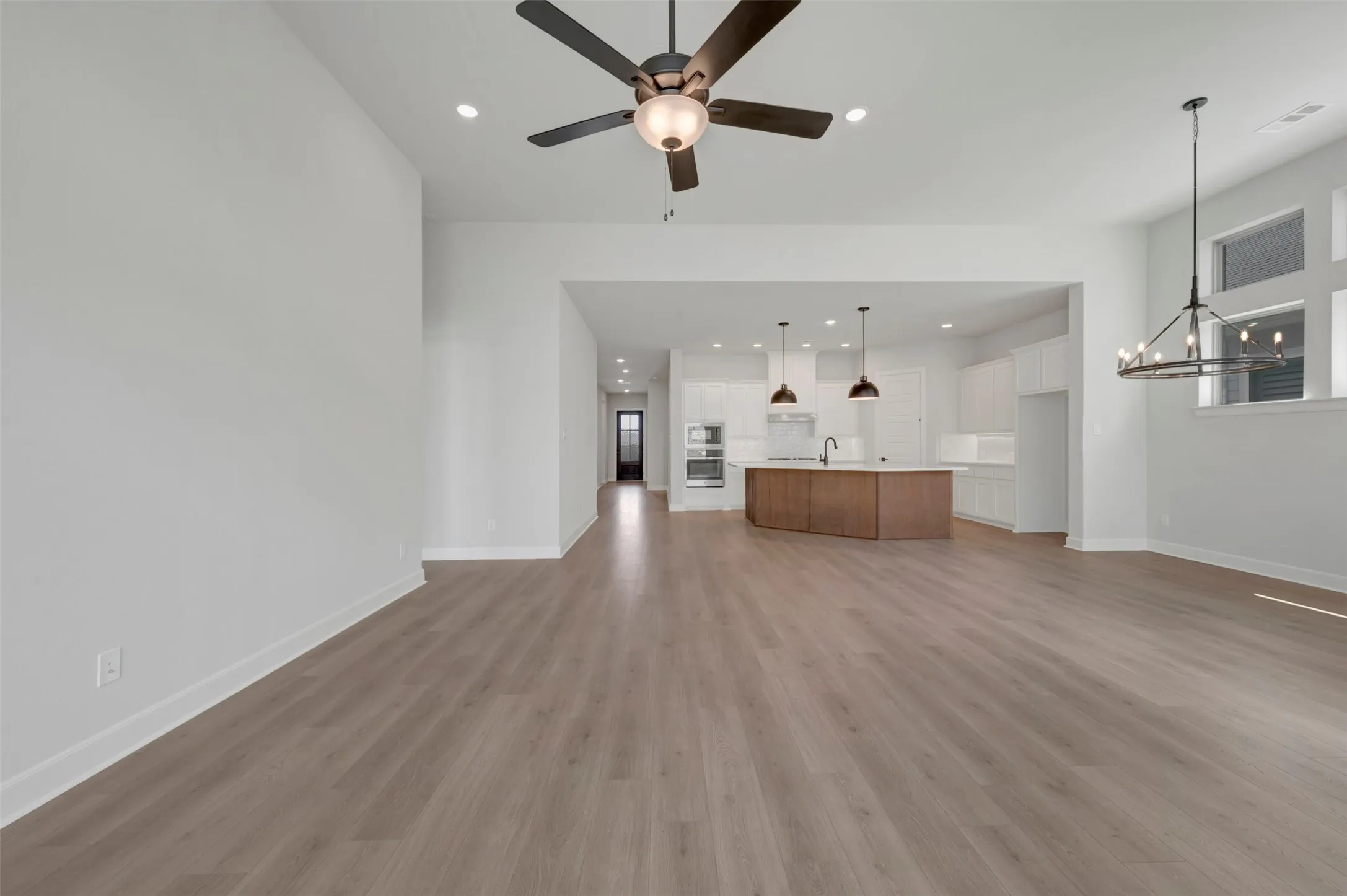 Open-concept living area featuring wood-finish flooring, a contemporary ceiling fan, and recessed lighting