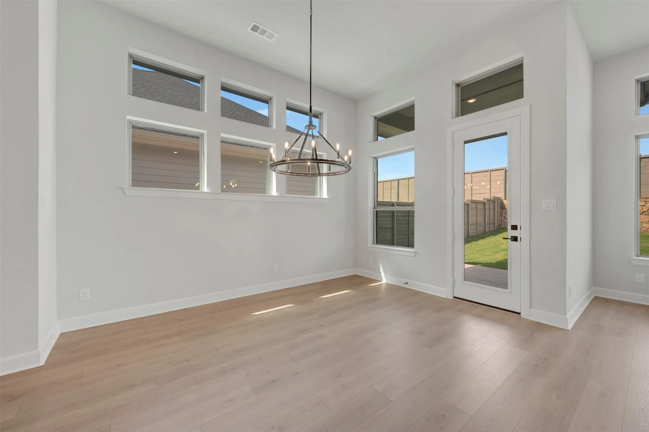 Expansive room featuring light wood-finish flooring and a series of strategically placed windows