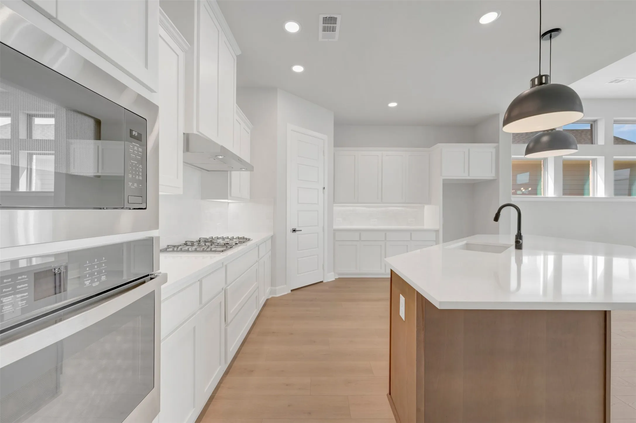 Bright kitchen featuring an expansive island with a matte black faucet and pendant lighting