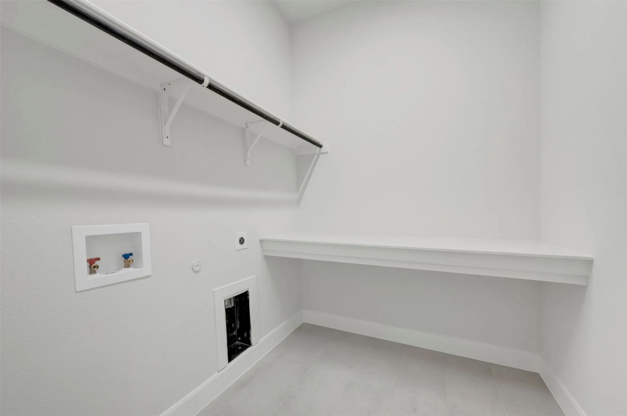 Utility room featuring a built-in shelf with hanging rod, a built-in countertop, and light gray tile flooring