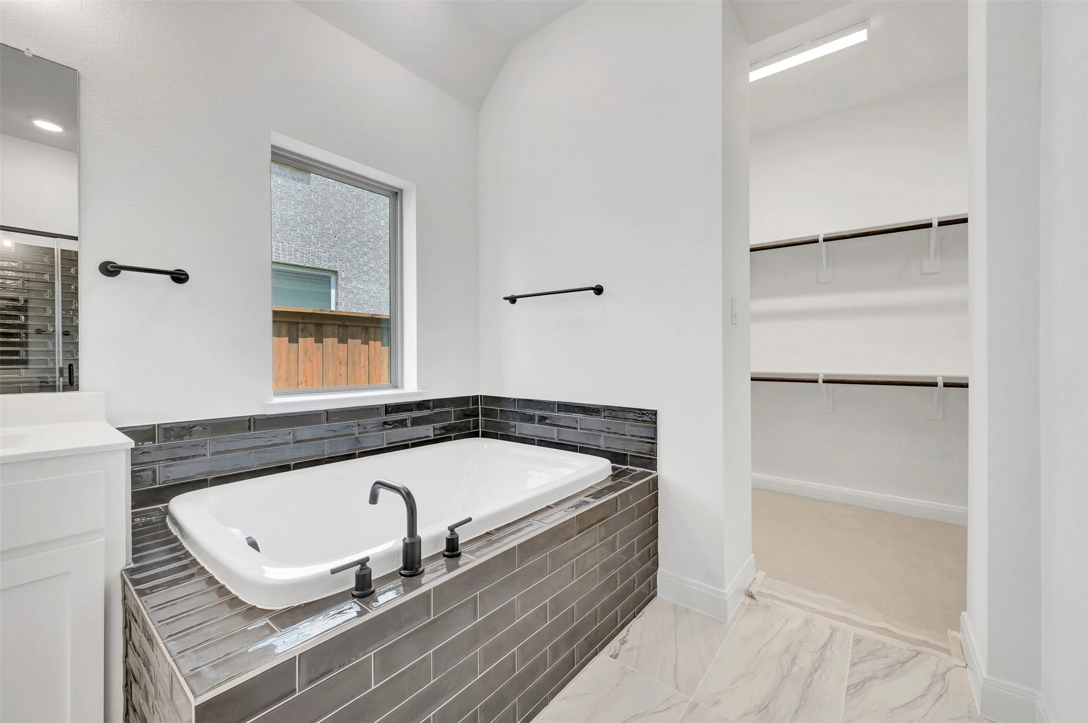Soaking tub with dark grey subway tile surround