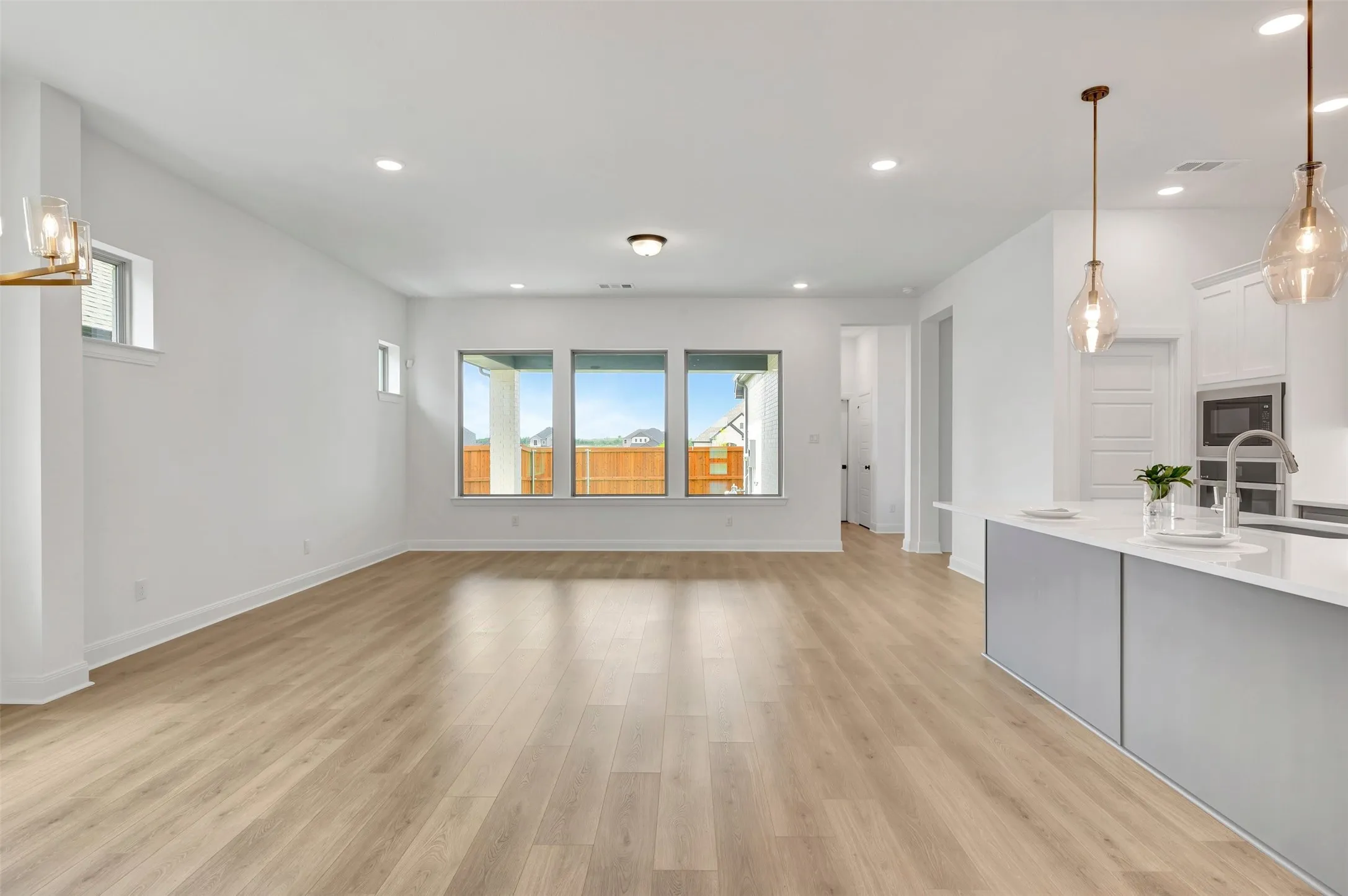Open-concept living space featuring wood-finish flooring, recessed lighting, and a kitchen island with pendant lighting