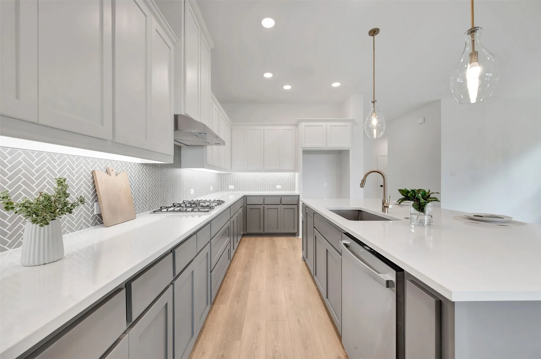 Expansive kitchen featuring wood-finish flooring, two-tone cabinetry, and light-toned countertops