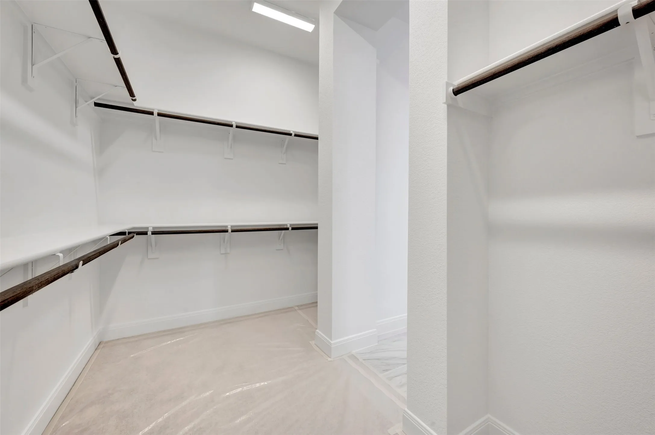 Walk-in closet featuring extensive shelving, multiple hanging rods, and light-colored flooring