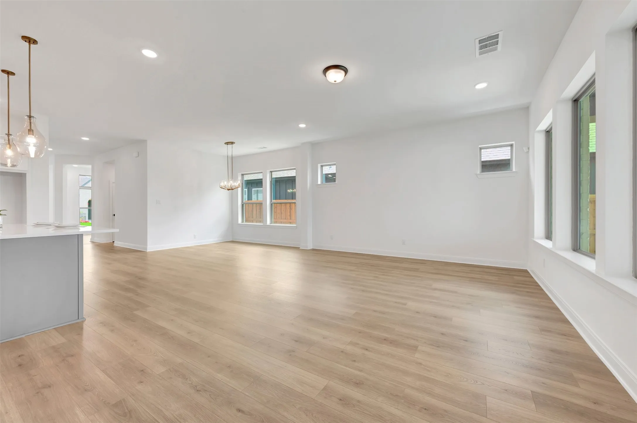 Expansive main living area featuring wood-finish flooring, white walls, recessed lighting, and multiple windows