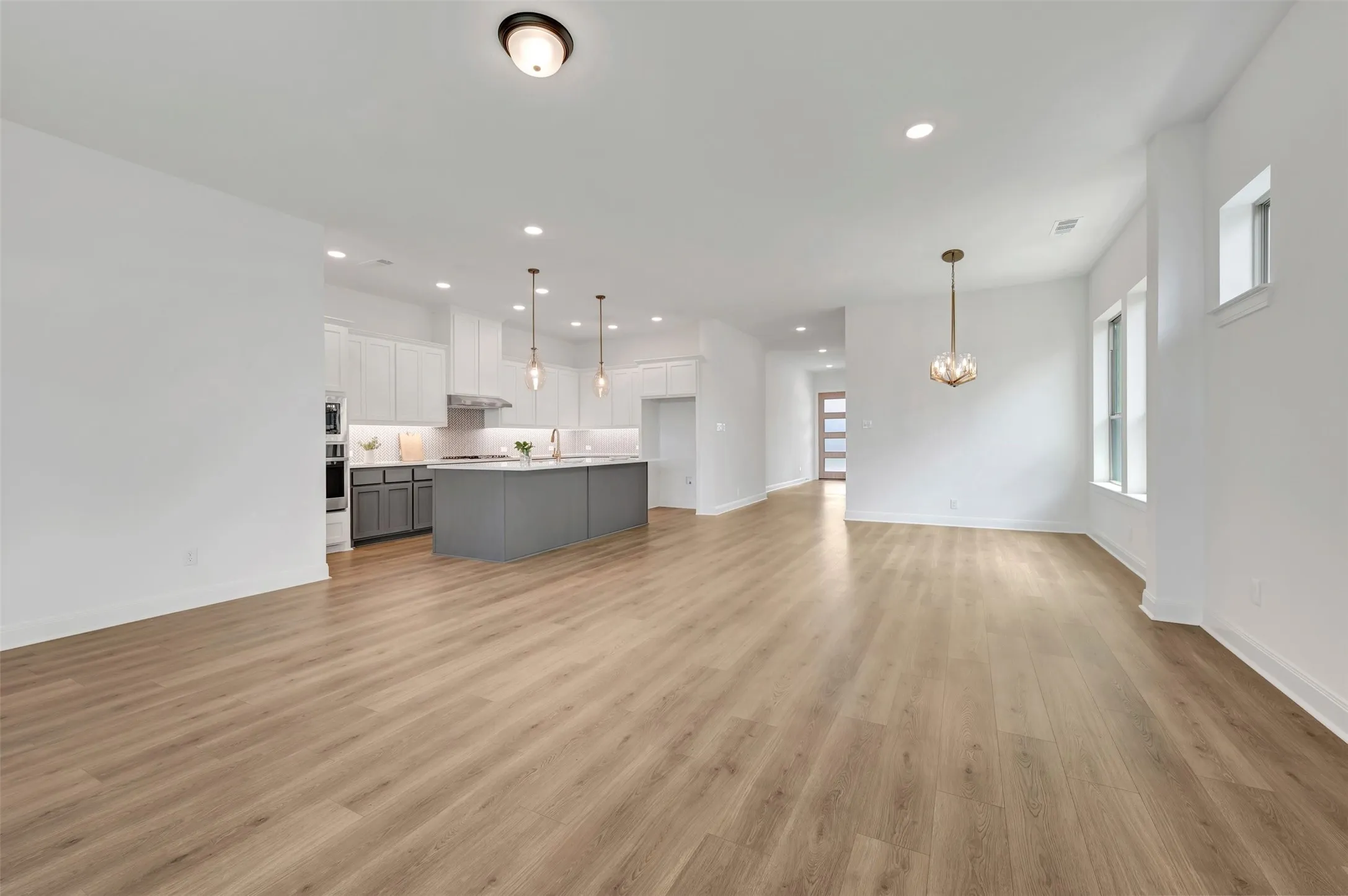 Open-concept living area featuring wood-finish flooring, recessed lighting, and a modern kitchen