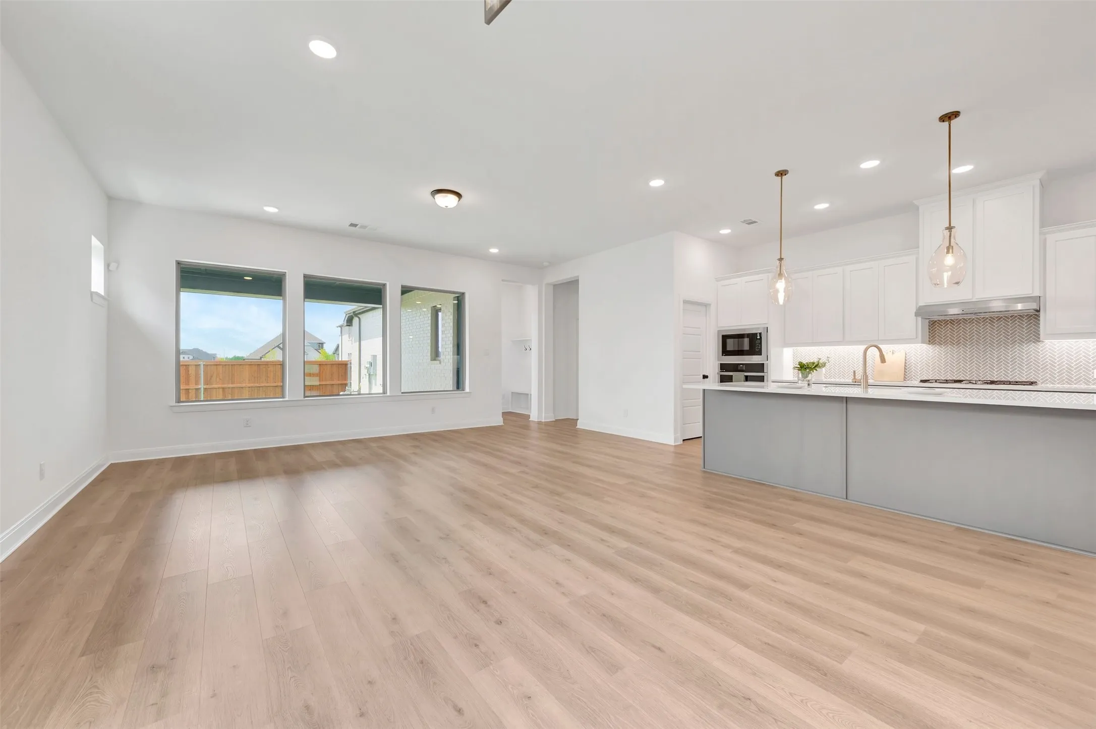Open-concept living area featuring light wood-finish flooring, recessed lighting, and a kitchen island with pendant lighting