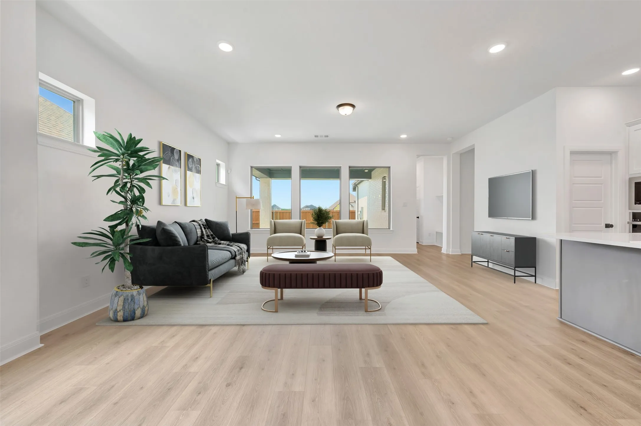 Spacious living area featuring light wood-finish flooring, recessed lighting, and large windows