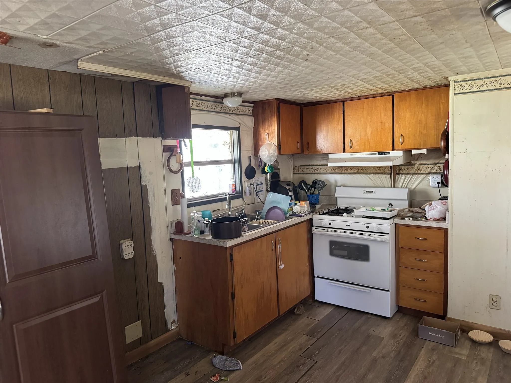 Kitchen with wood finish cabinetry, white range with gas cooktop, light countertops, and dark wood-style flooring