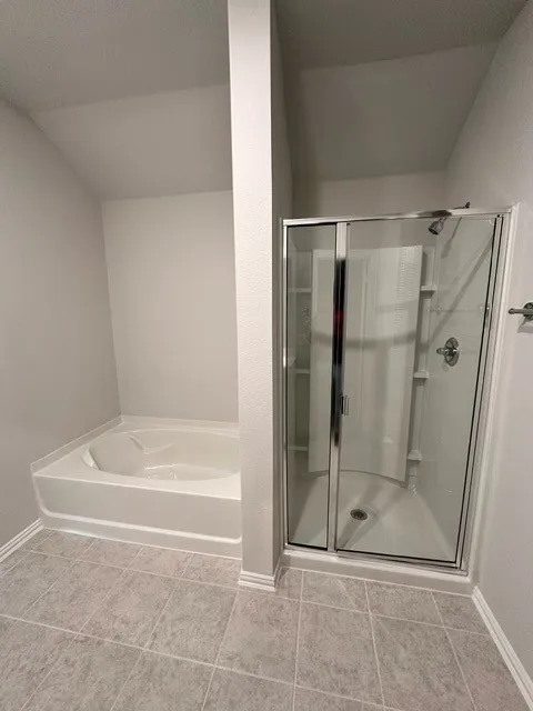 Bathroom featuring a garden tub, a shower stall, and vaulted ceiling