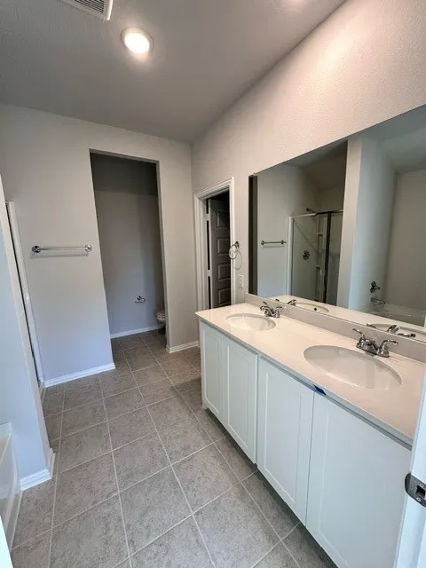 Bathroom featuring double vanity, a stall shower, light tile patterned floors, a garden tub, and recessed lighting