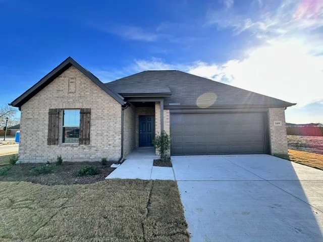 View of front of property featuring brick siding, an attached garage, and driveway