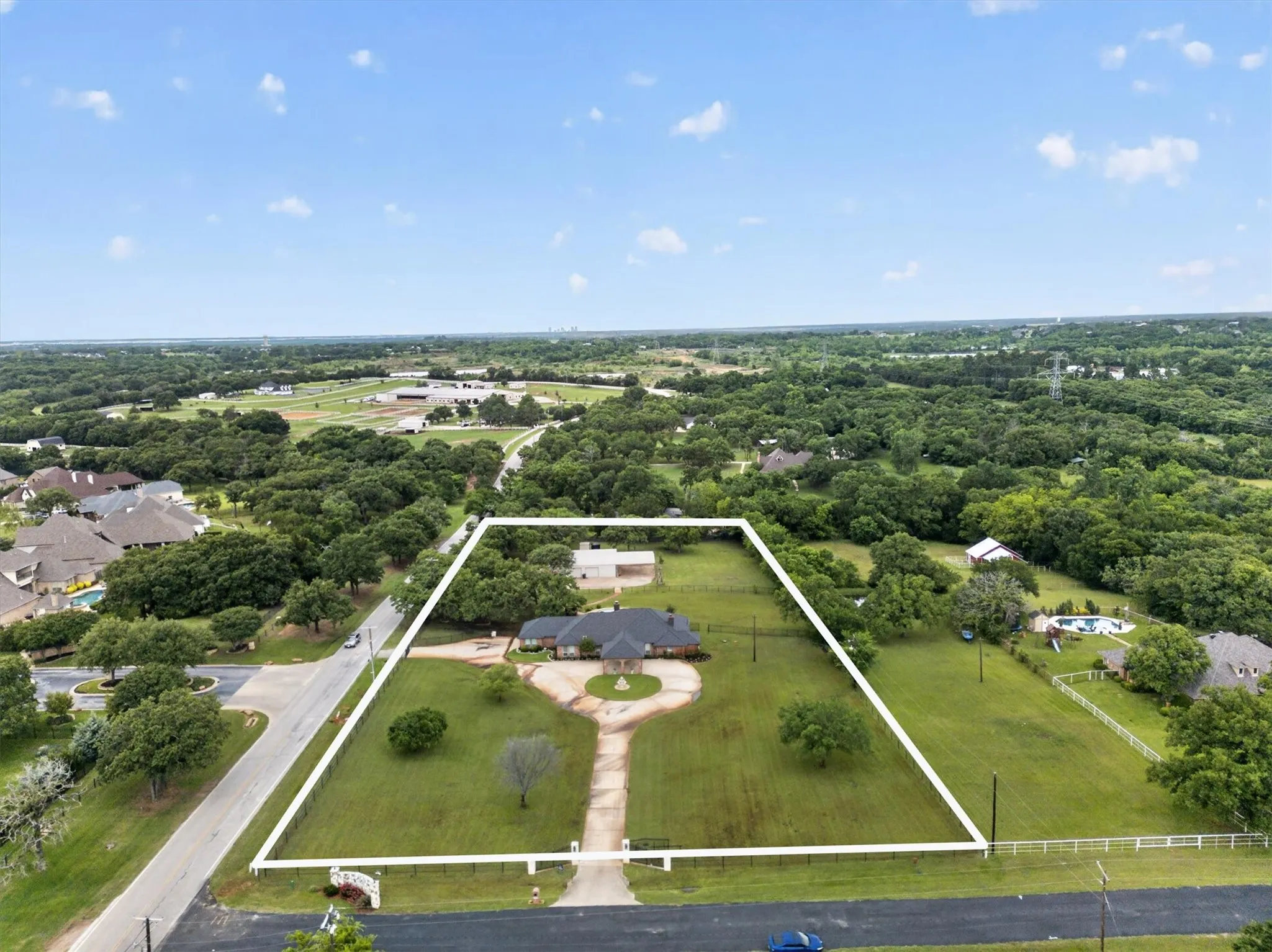 Expansive estate property featuring a brick residence, circular driveway, detached outbuilding, and mature trees