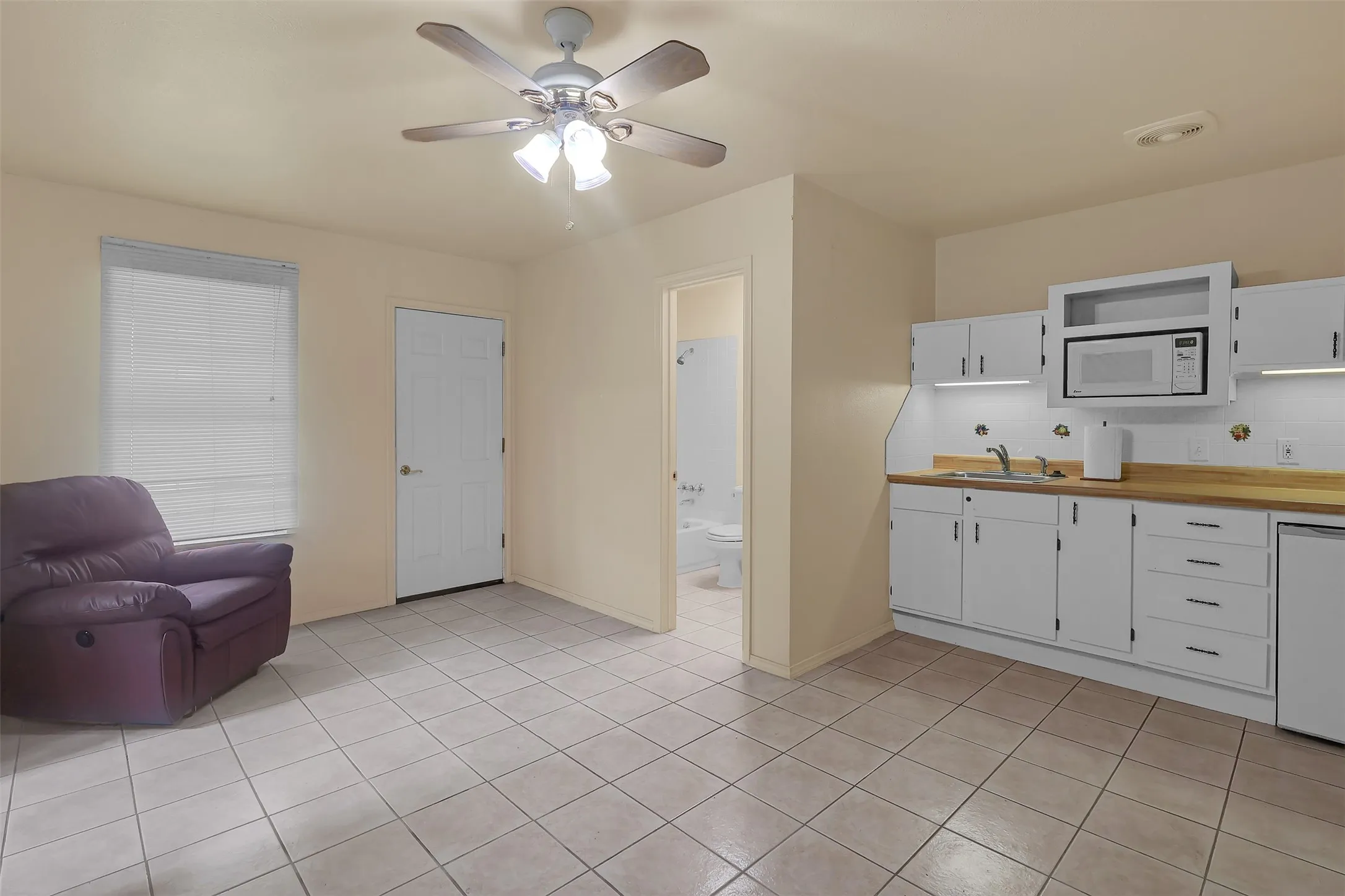 Kitchen featuring white cabinetry, white microwave, ceiling fan, dishwasher, and light tile patterned floors