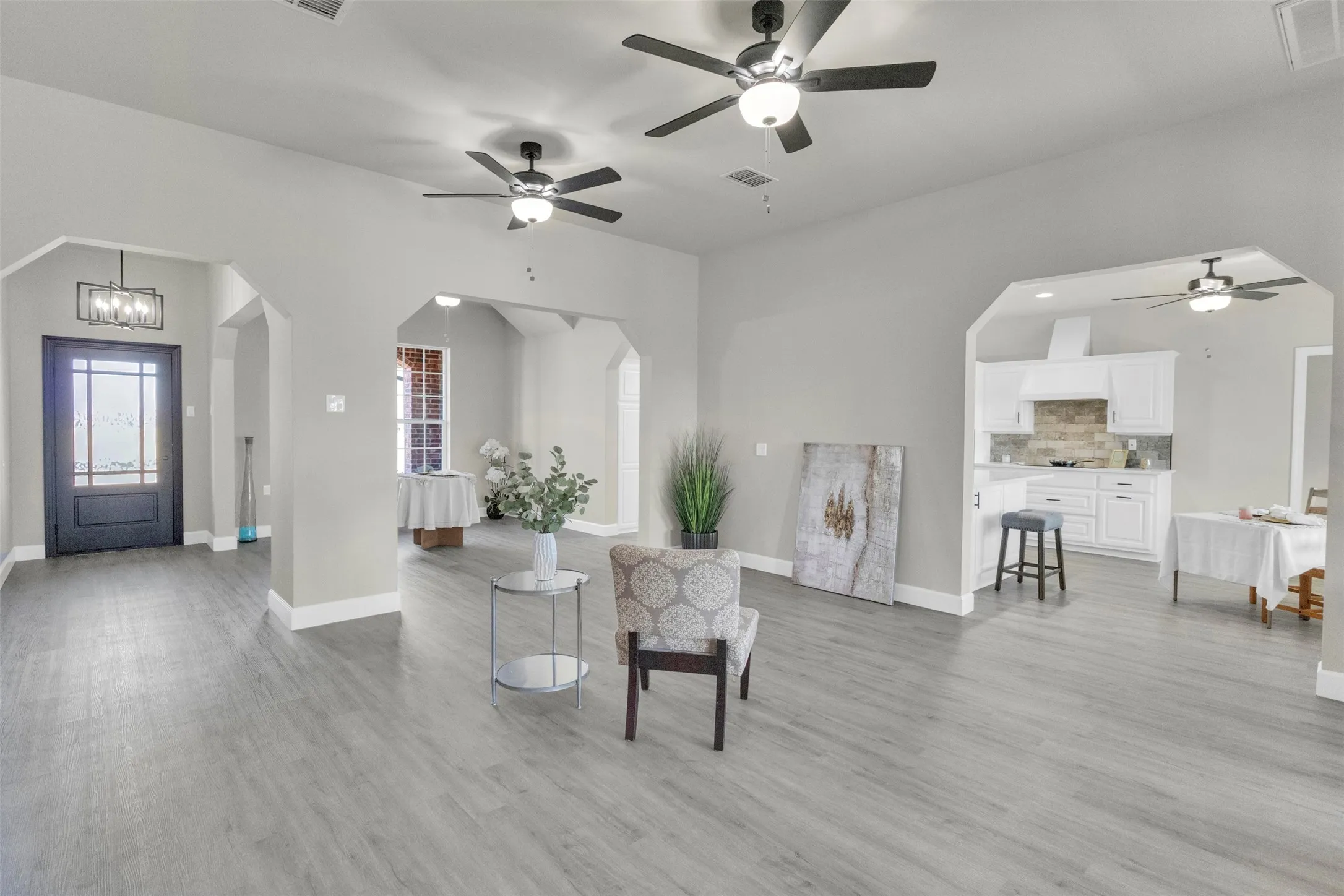 Living area with ceiling fan, arched walkways, light wood-type flooring, and hanging lights