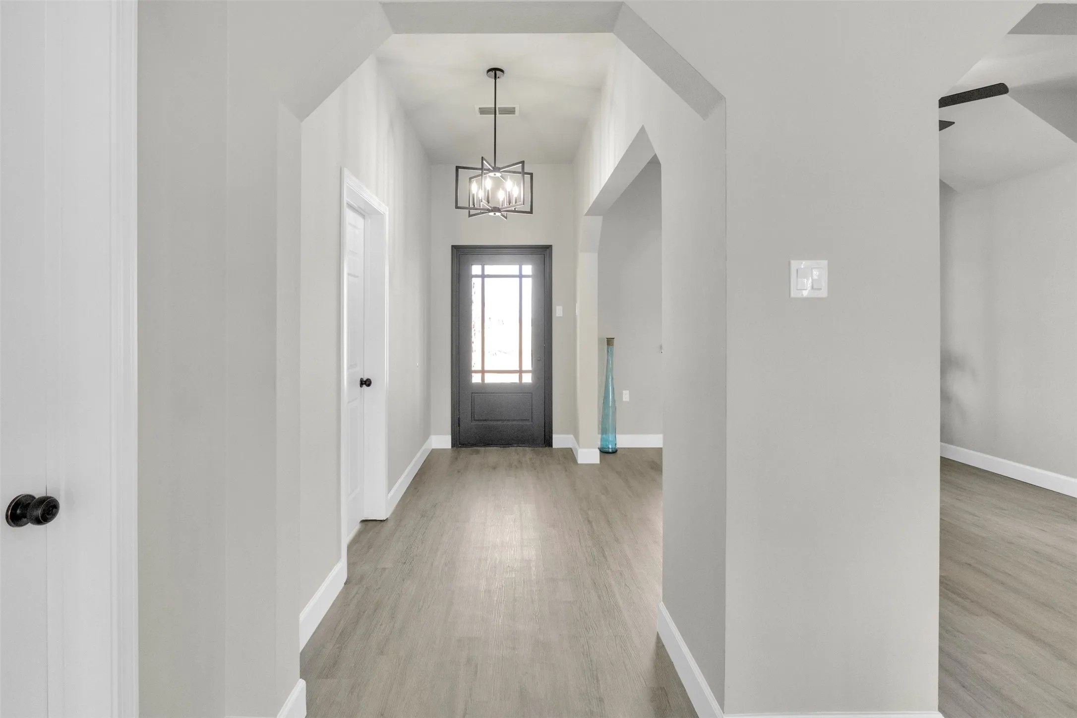 Entryway with suspended lighting and light wood-style flooring