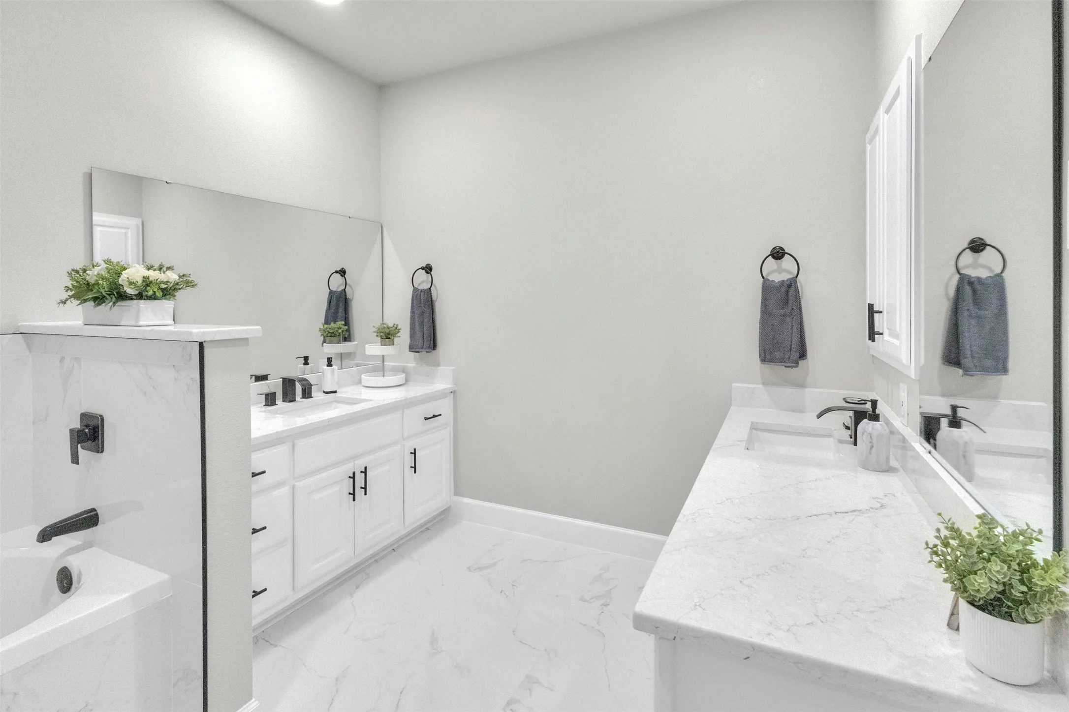 Full bath featuring a bath, two vanities, recessed lighting, and light marble finish flooring