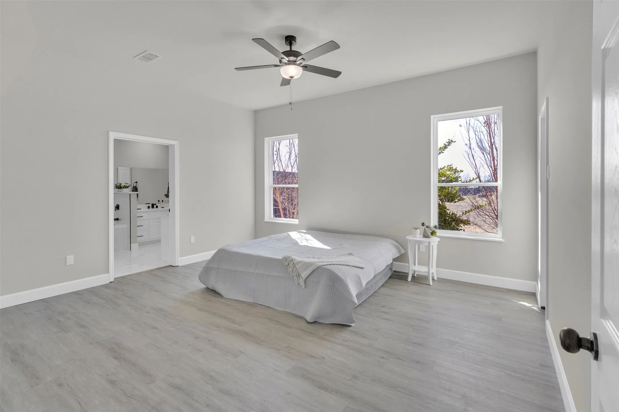 Bedroom featuring a ceiling fan, light wood finished floors, and ensuite bath