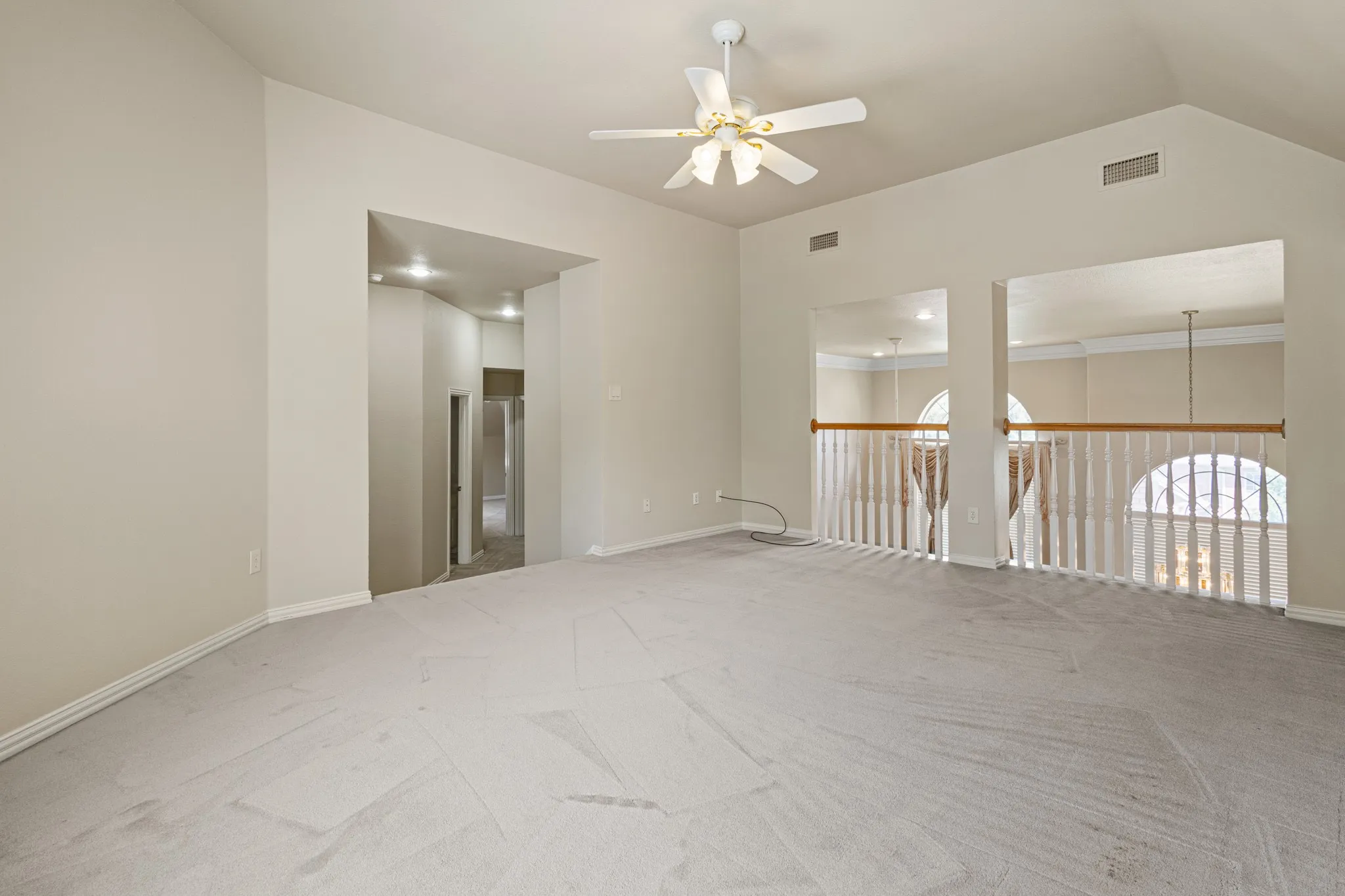 Carpeted spare room featuring ornamental molding, ceiling fan, and vaulted ceiling