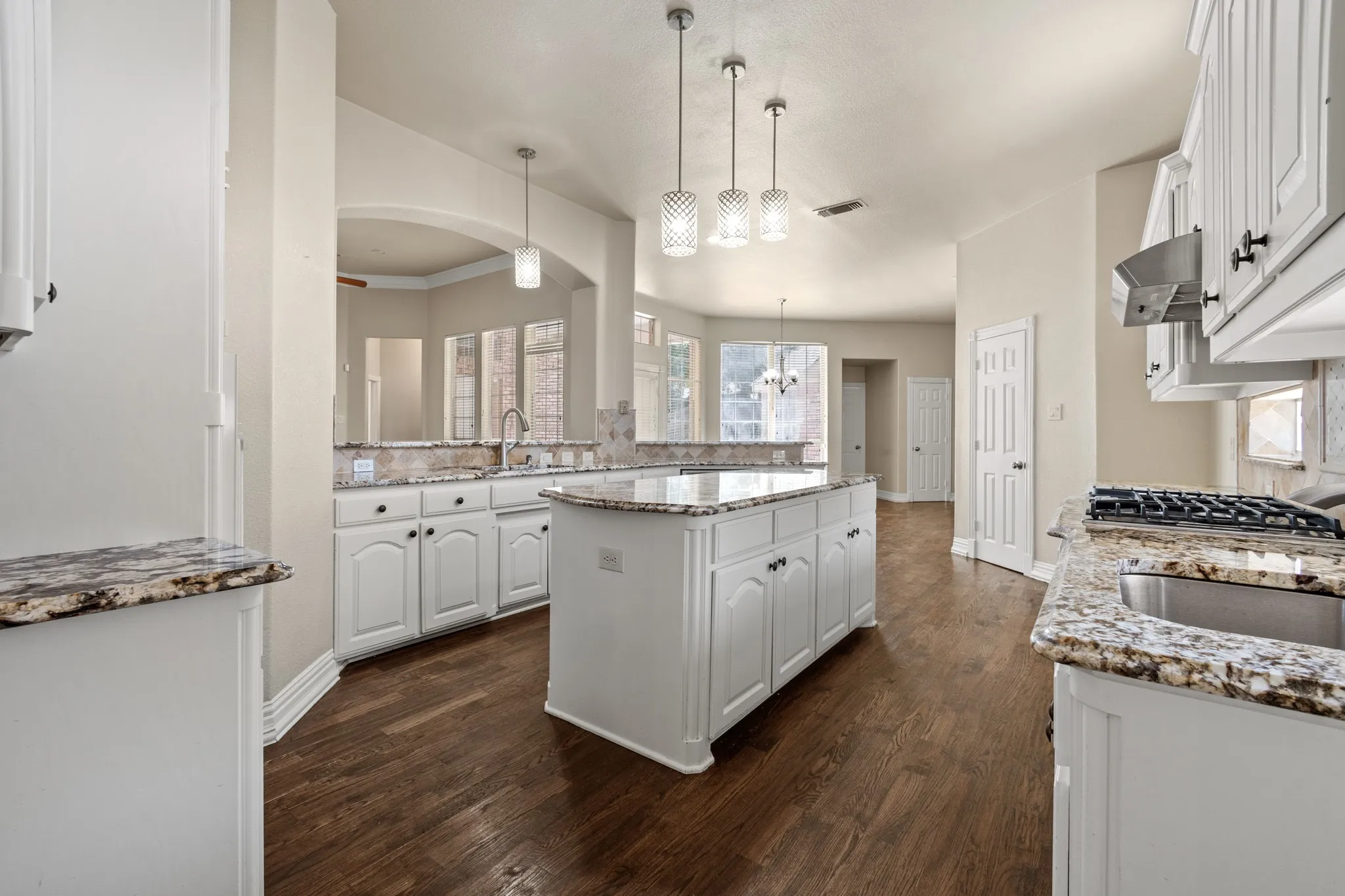 Kitchen featuring hanging light fixtures, extractor fan, a center island, dark wood-type flooring, and white cabinets