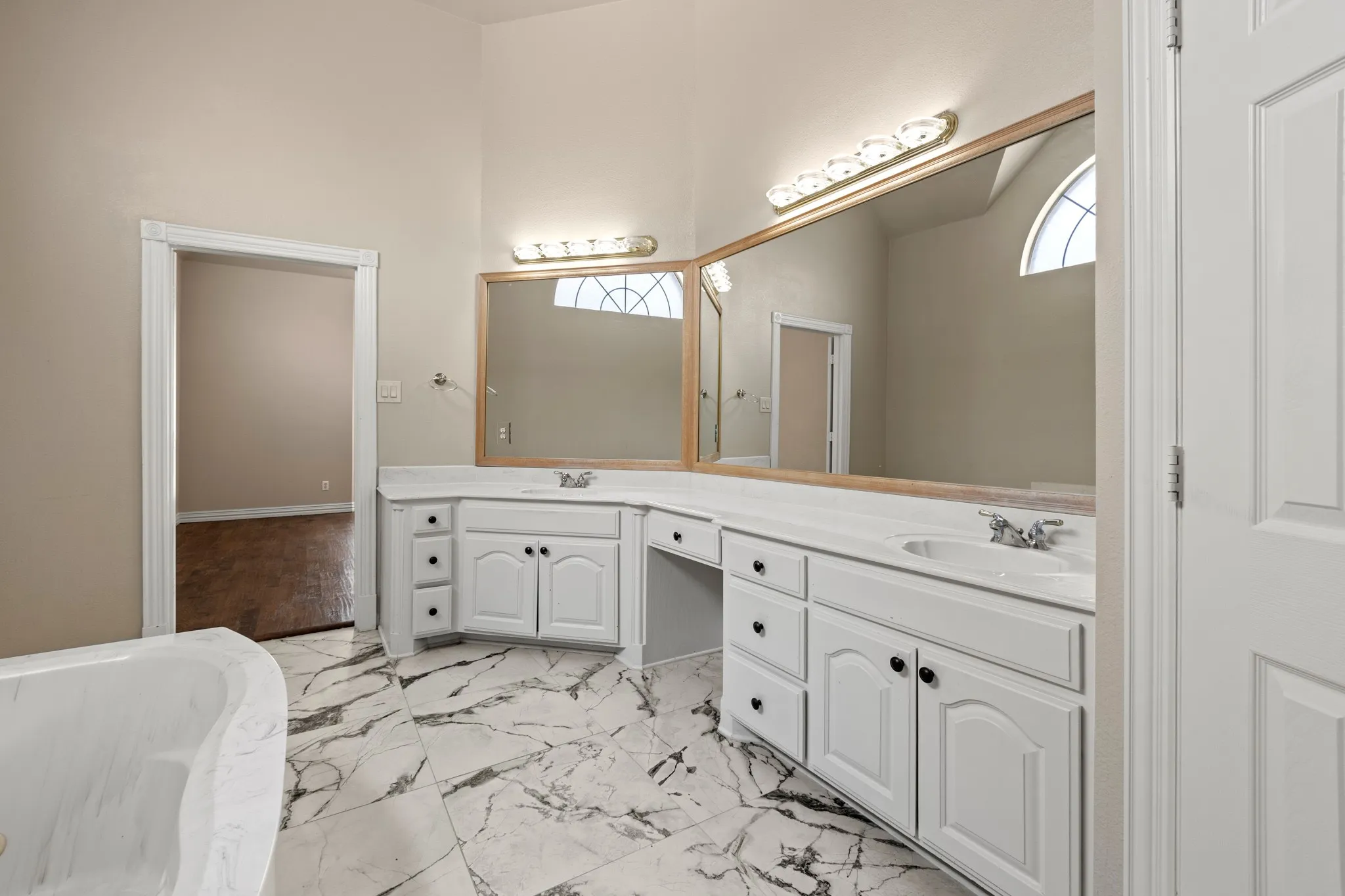 Primary Bathroom with tile floors, dual sinks, oversized vanity, and a bath to relax in